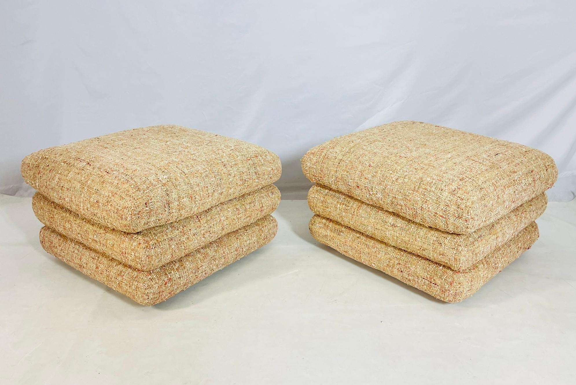 Un par de atrevidos y esculturales pufs o taburetes vintage de los años 70, que se distinguen por su juguetón diseño de cojines apilados. Tapizadas en un tejido de rica textura, estas piezas presentan cálidos tonos neutros acentuados por sutiles