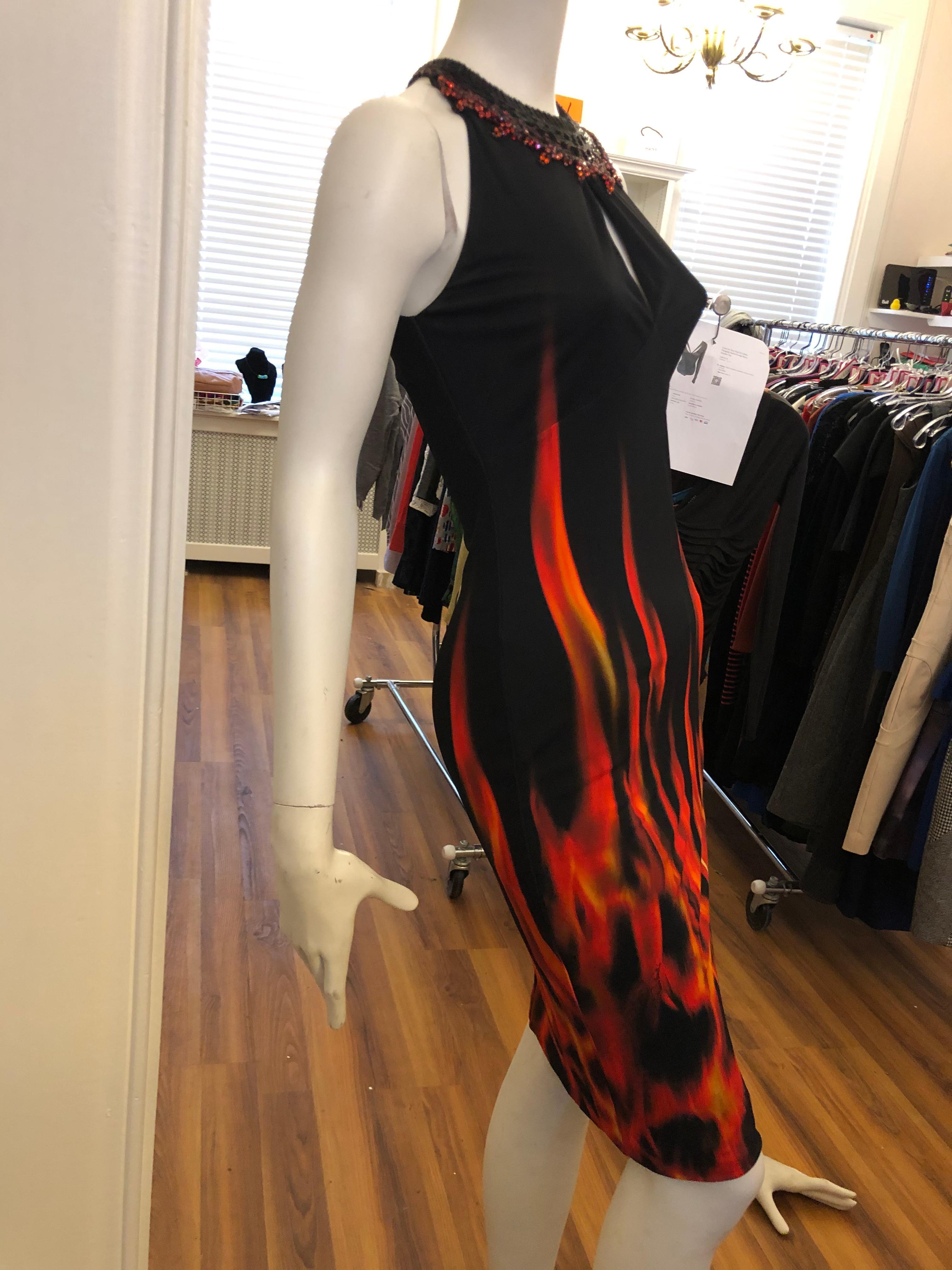 Jersey viscose and silk knee length dress with wonderful neckline with a flame design. There is also a peek-a-boo slit at the chest. The dominant colors are black and red with flashes of orange. There is a lining and a zip closure at the back.

You