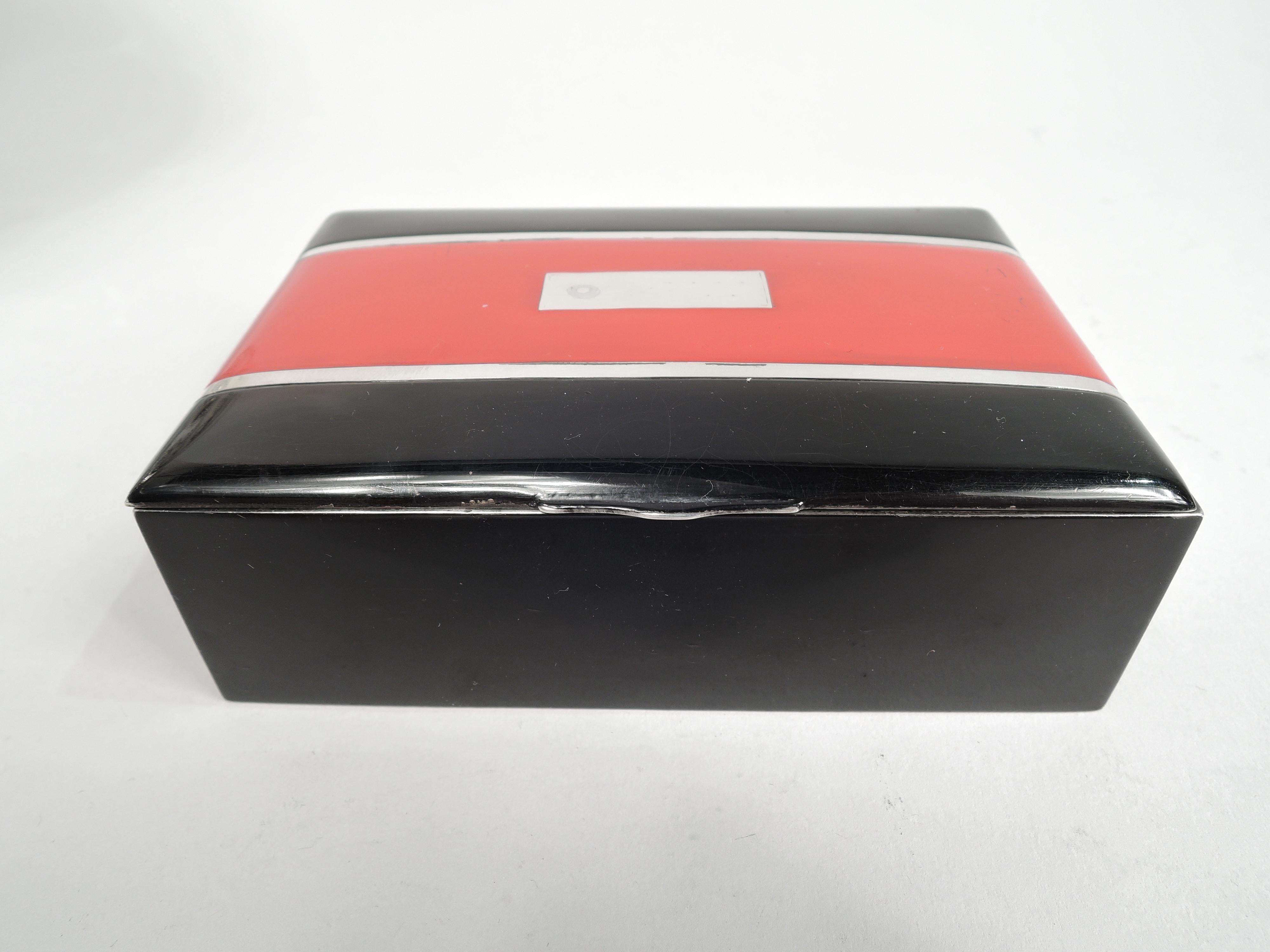 Striking Art Deco sterling silver and enamel box. Made by Thomae in Attleboro, ca 1925. Rectangular with straight sides. Cover hinged and gently curved. Sides black. Cover top same with wide red stripe with central silver rectangular frame (vacant)