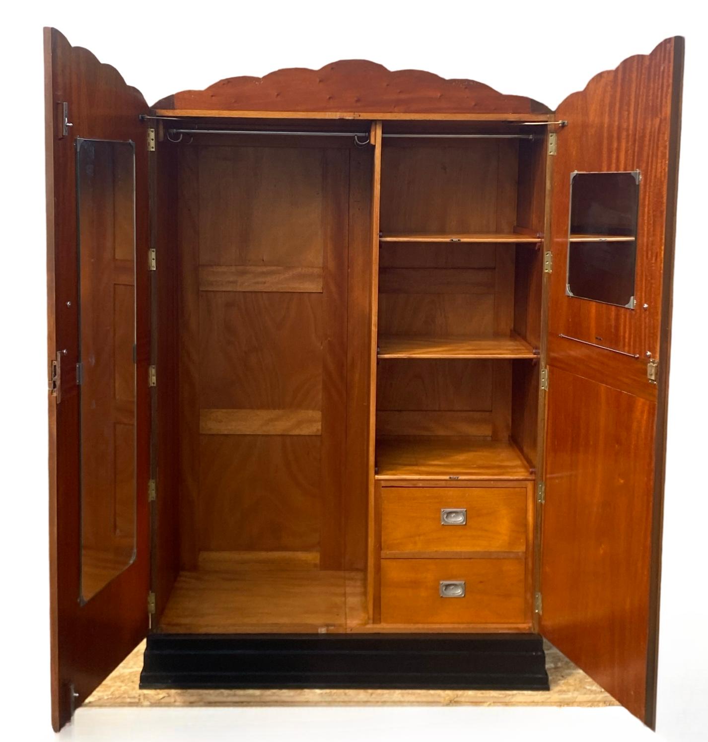 An unusual and eye catching Art Deco double wardrobe with straight grain walnut veneers to the front and sunburst design with iconic cloud outline. The central decorative panel boast a claret coloured burl walnut band. The whole is raised on a