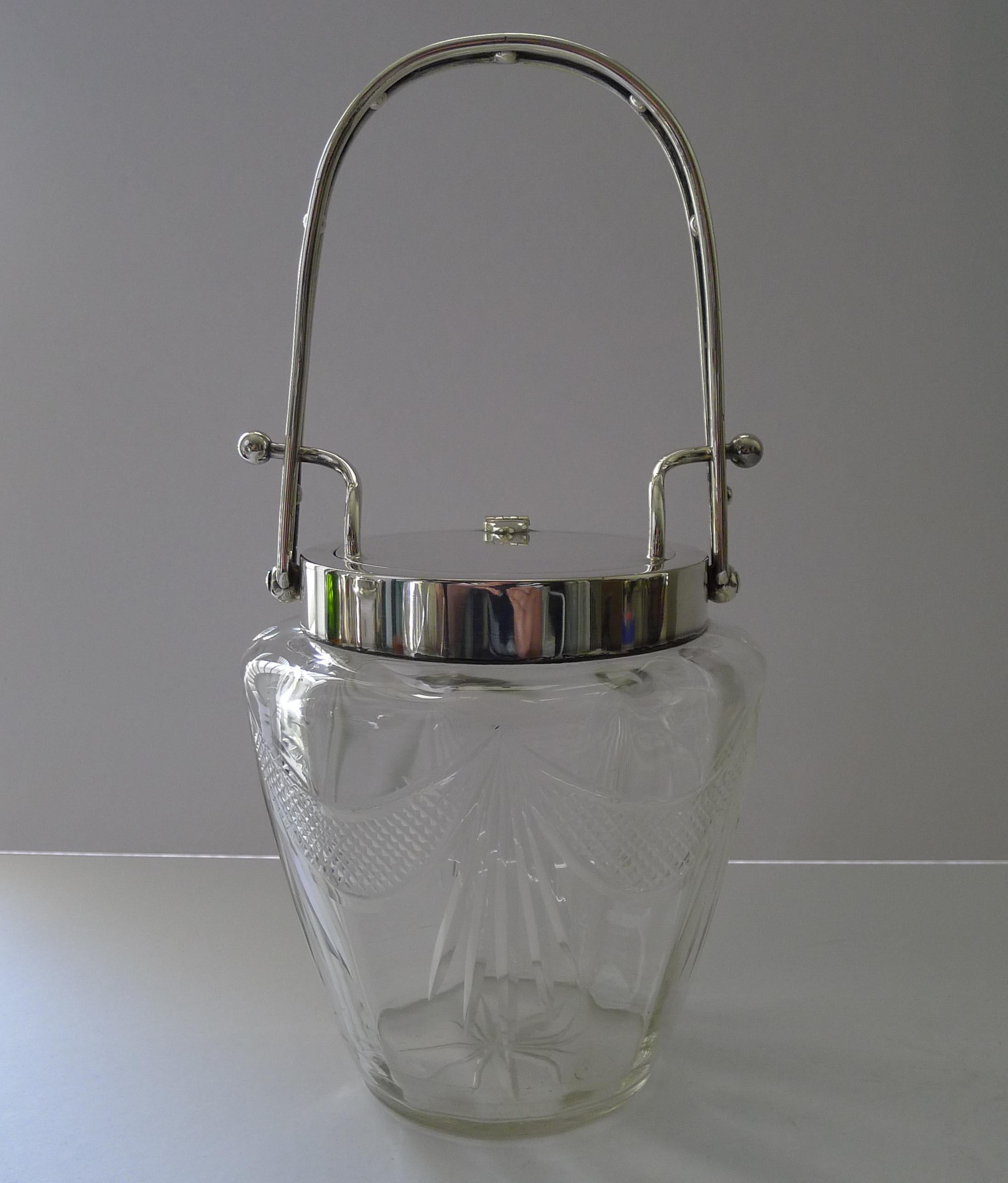 A beautiful example of an English Edwardian biscuit box or barrel, made from hand-cut glass and silver plated fittings.

The tall handle moved downwards opens the hinged lid, the underside marked 
