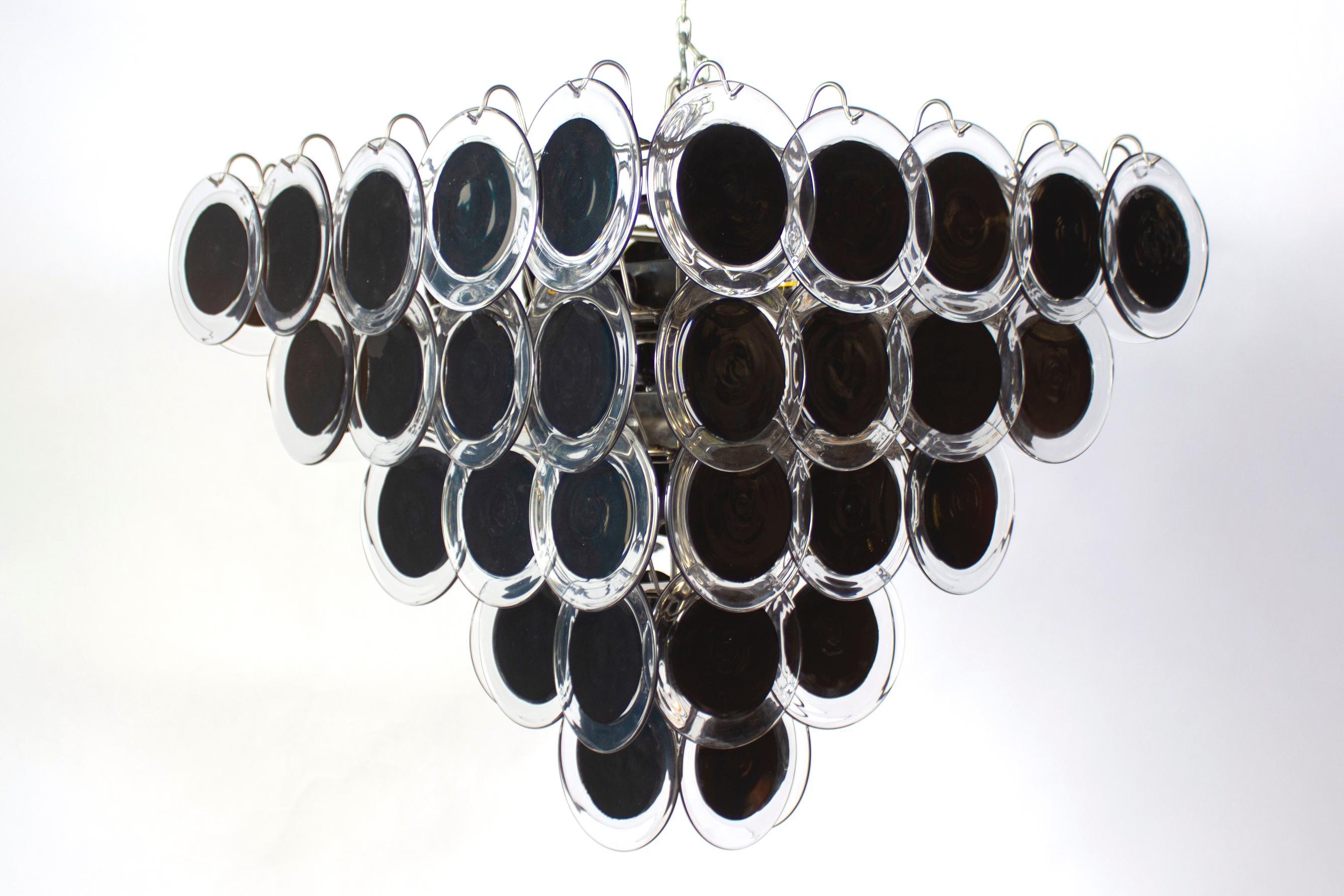 Black  Murano glass disc chandelier in pyramid shape. 
Each chandelier is made of 60 black discs of precious Murano glass and arranged on five levels.
Customization is available in different sizes, finishes and glass colors.
 Nine  light bulbs E 27.
