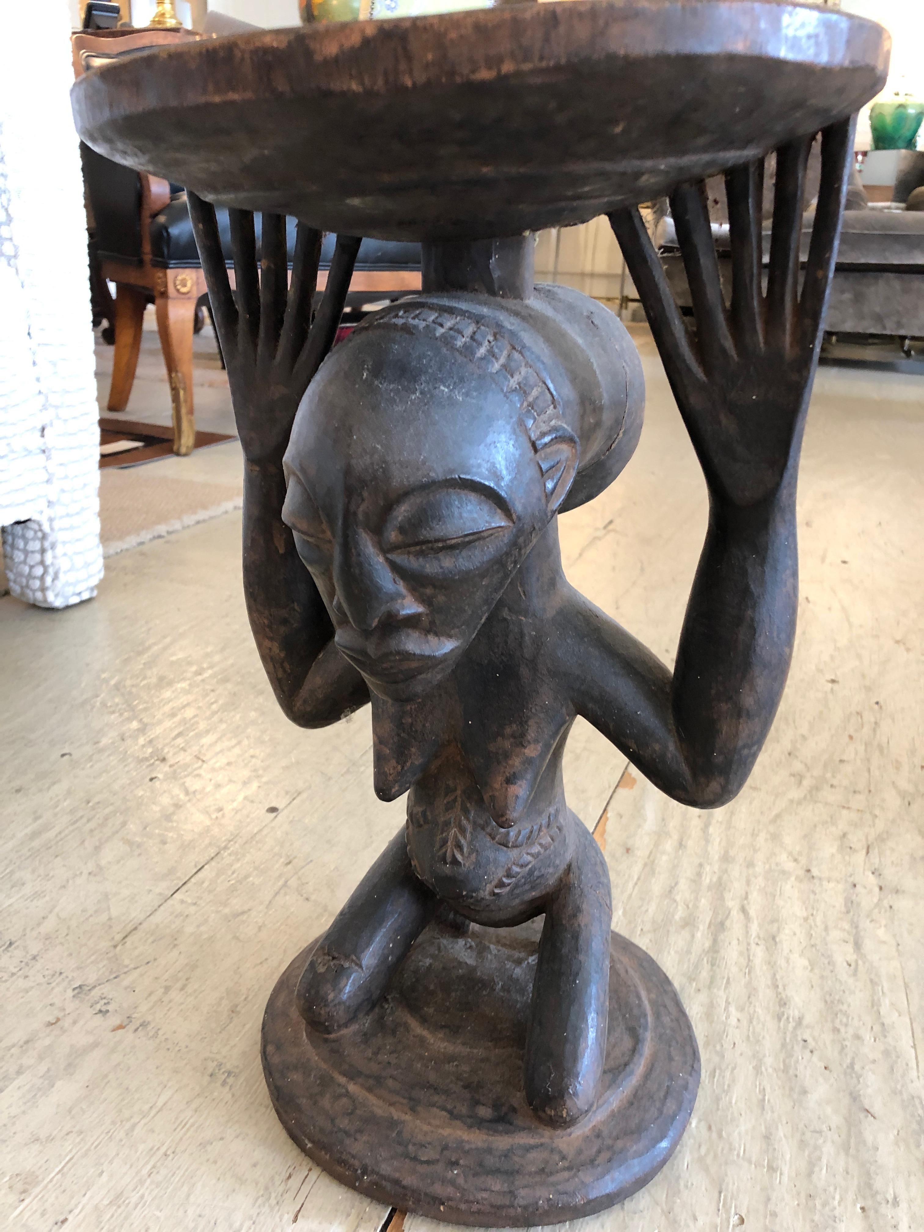 A small round carved wood drinks or accent table having a tribal African figure as the base with lovely spread fingers holding up the top surface.
Note: A slightly varied pair are available.