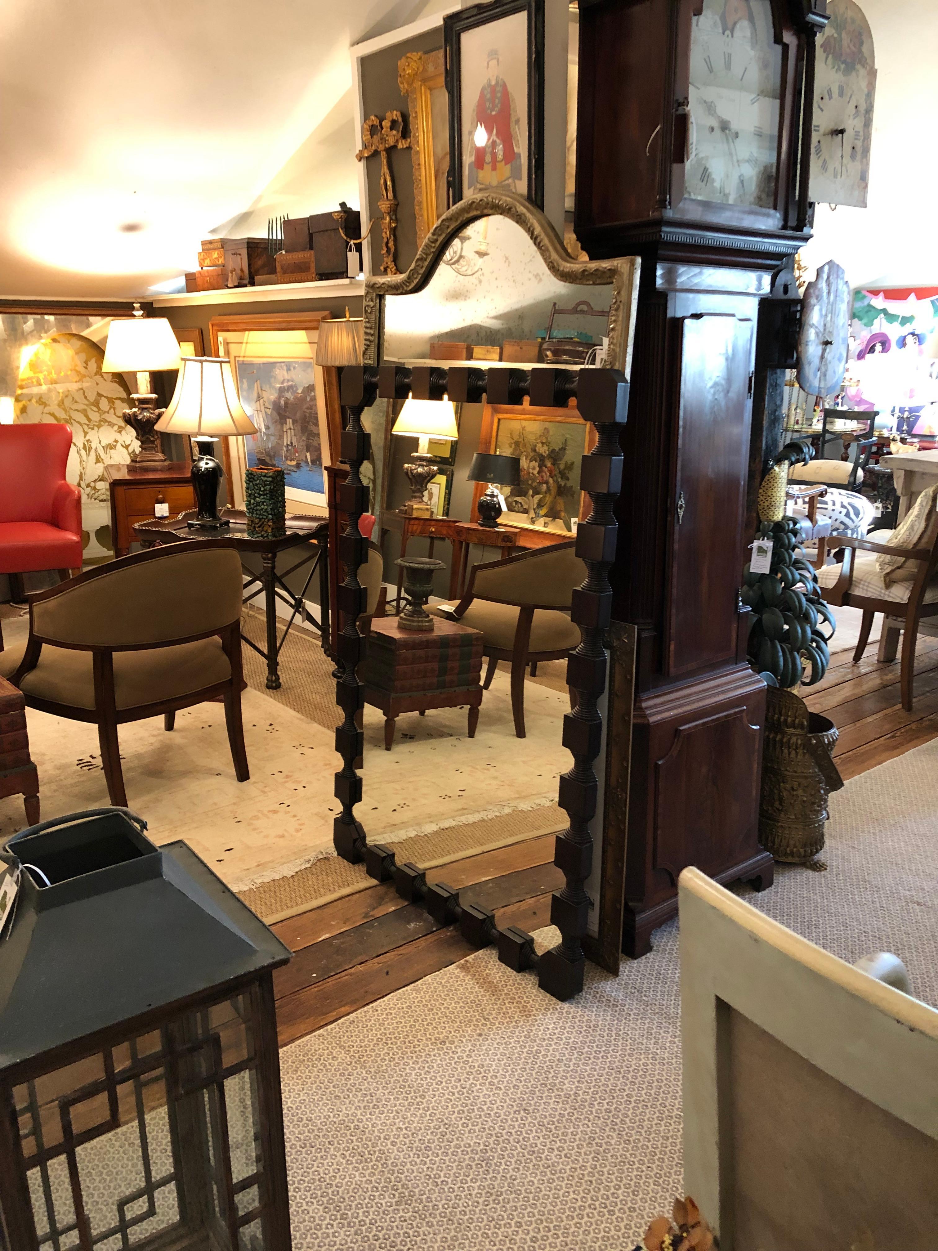 A big bold yet organic feeling dark carved wood rectangular mirror by Celerie Kemble having chunky blocks connected by turned wood. Rich and gutsy. Has french cleats on the back so can be oriented vertically or horizontally.