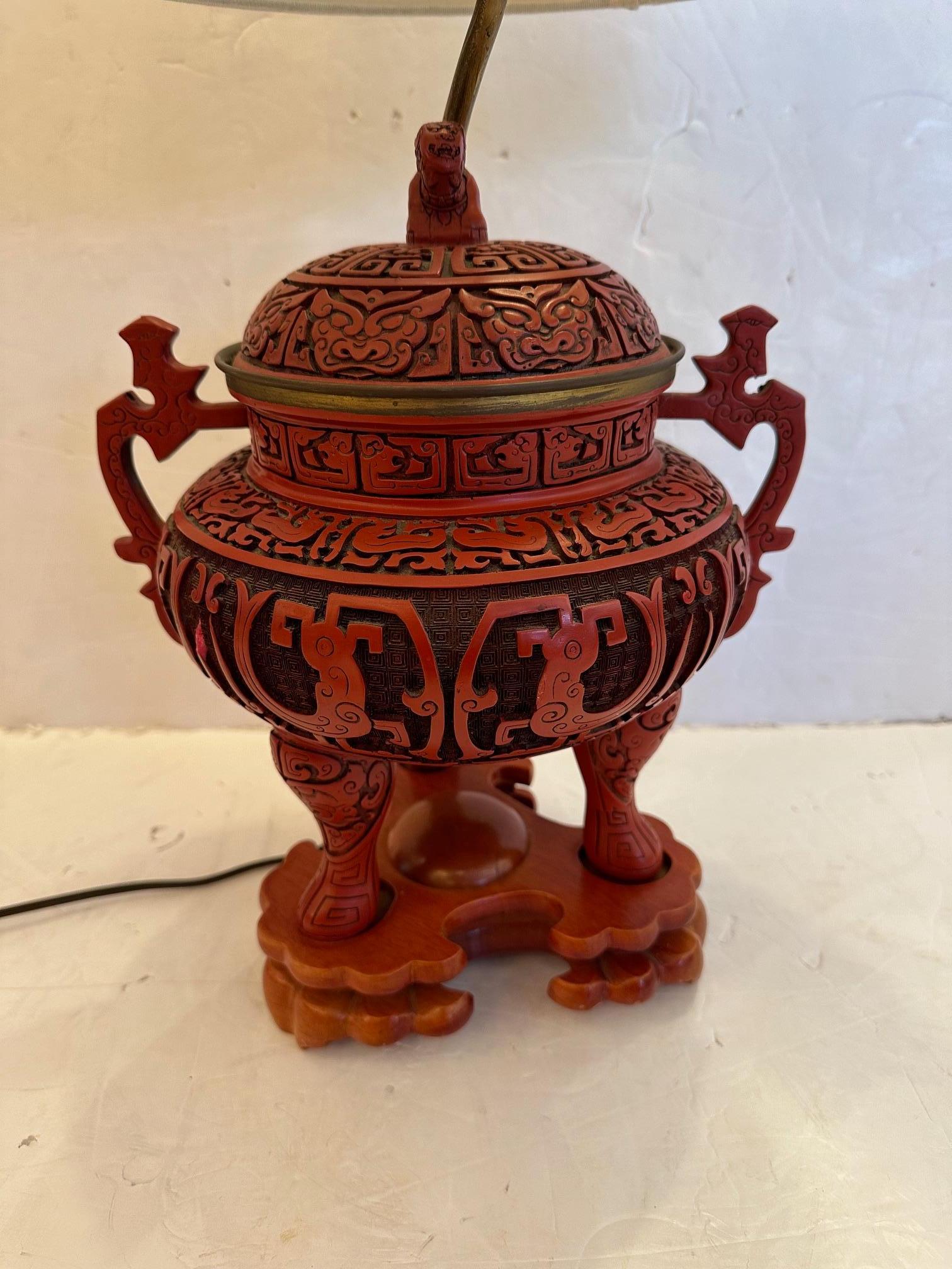 Striking red carved wood Chinese cinnabar table lamp having a sculptural round lidded urn like shape with handles and detailed foo dog finial as well as 3 carved feet.
27.5” H to finial x 12” W x 10” D
Shade 15” Diameter x 9” H
