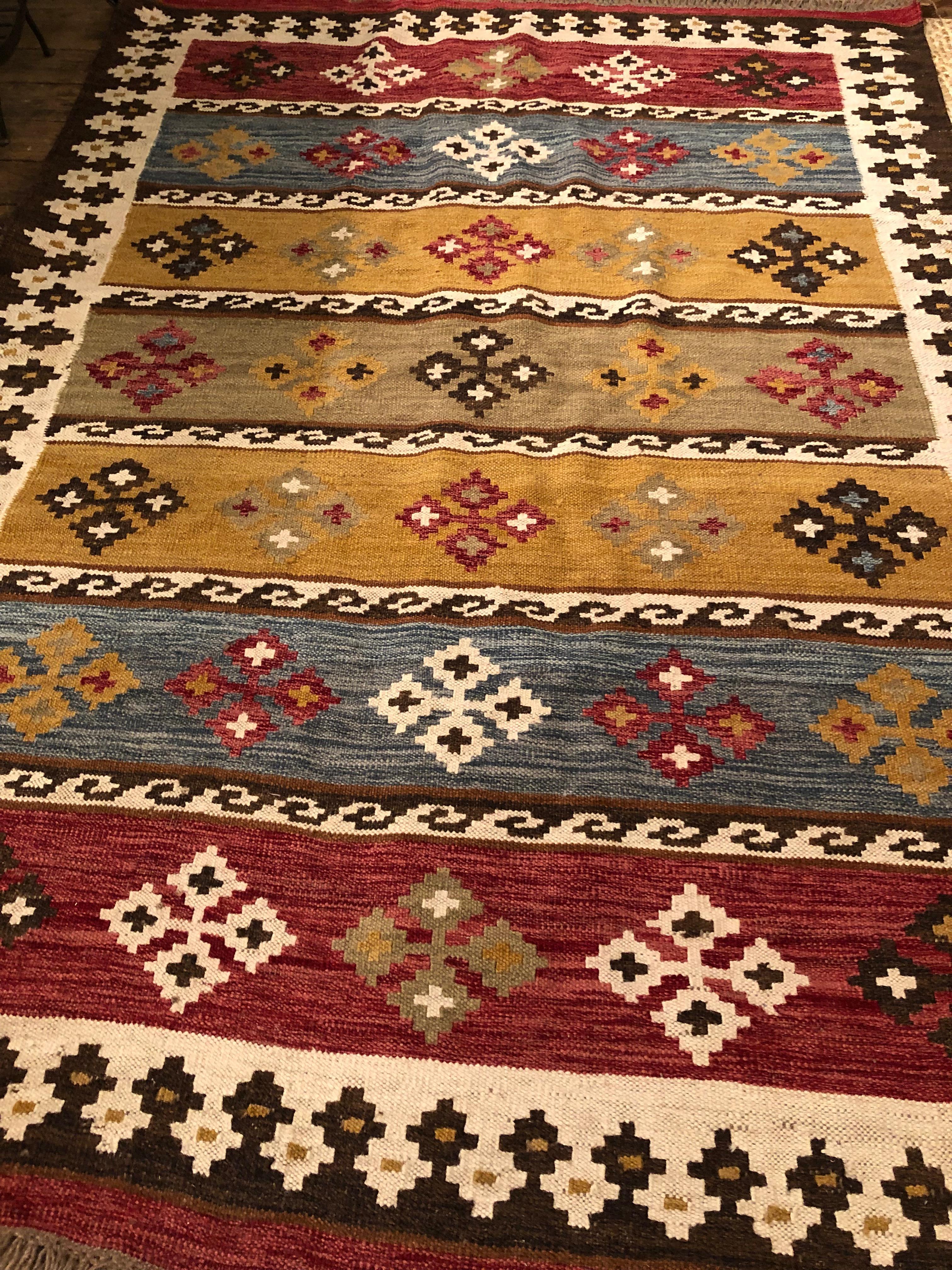 A gorgeous vintage kilim rug, newly cleaned, having warm combination of rust, mustard, brown, blue and cream color palette.