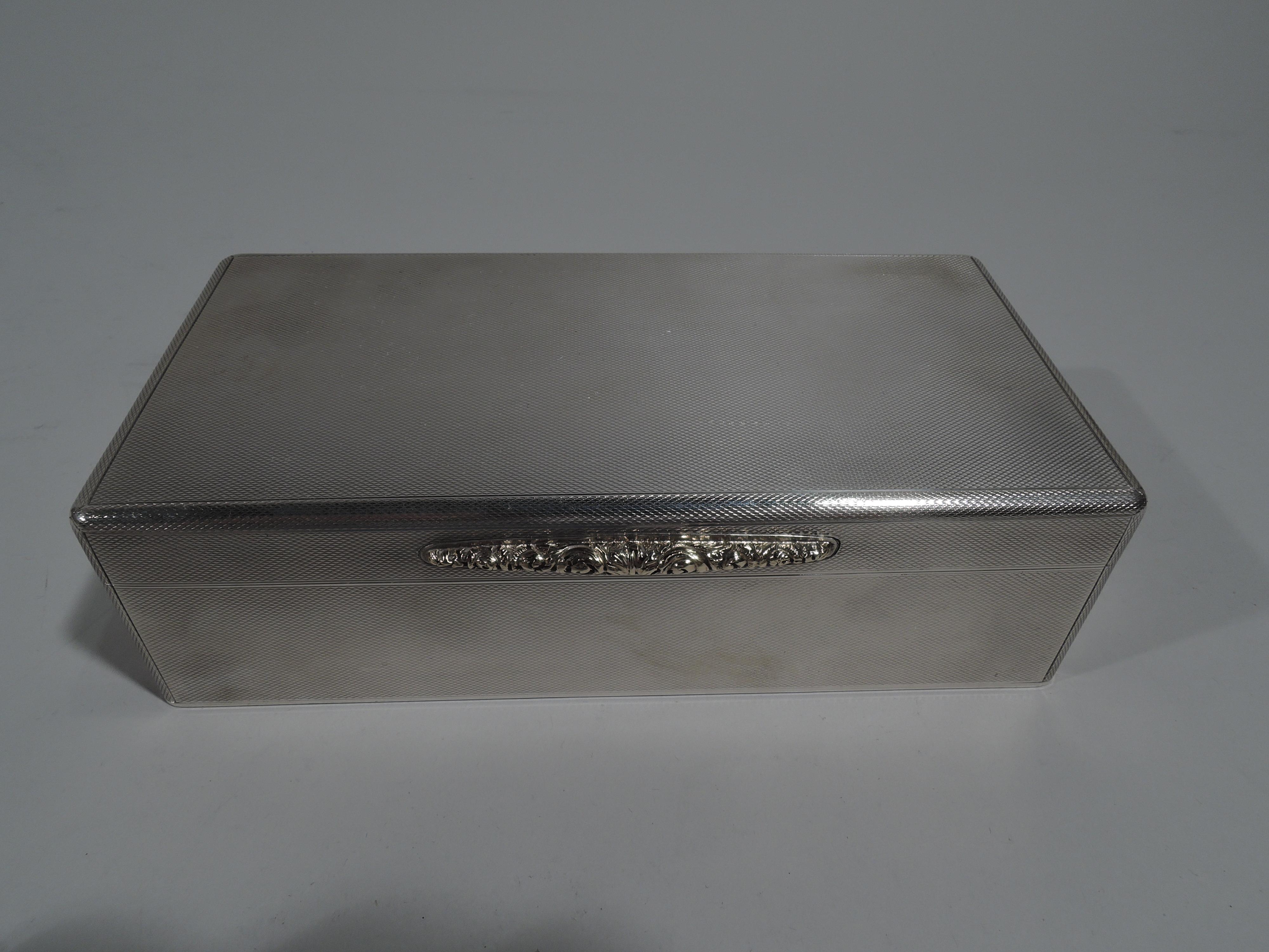 Edward VIII sterling silver box. Made by Padgett & Braham in London in 1936. Rectangular with straight sides and hinged and flat cover. All-over engine turned ornament. Tapering gold tab with tooled floral ornament. Box interior cedar lined and