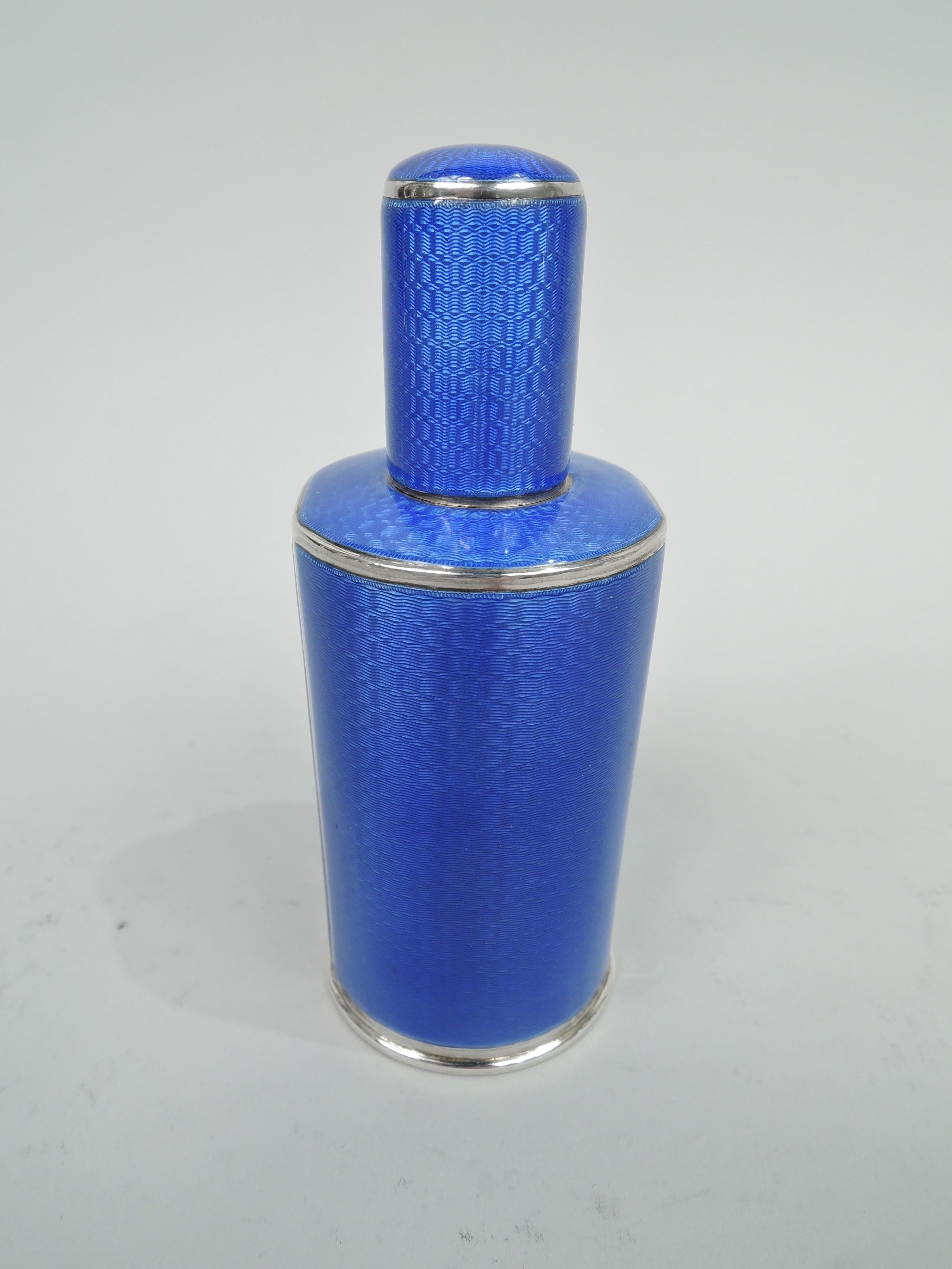 George V sterling silver perfume. Made by Adie Bros Ltd in Birmingham in 1930. Round and cylindrical with two easy-grip flattened sides, inset cylindrical neck, and cover. Blue guilloche enamel in sterling silver frames. Detachable clear glass