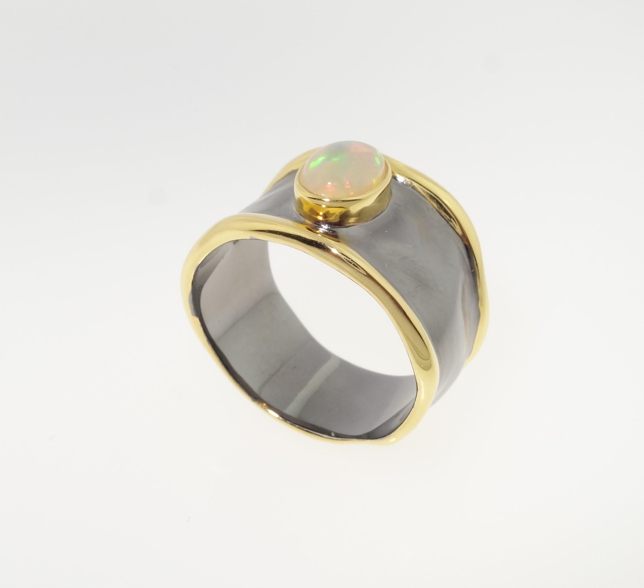Beautiful Solitaire ring featuring an Ethiopian Opal;  approx.  0.42 carat; Sterling Silver Tarnish-resistant Rhodium and gold accents on either side of mounting; Size 7. Stylish, Classic and Classy…illuminating your look with Timeless Beauty!