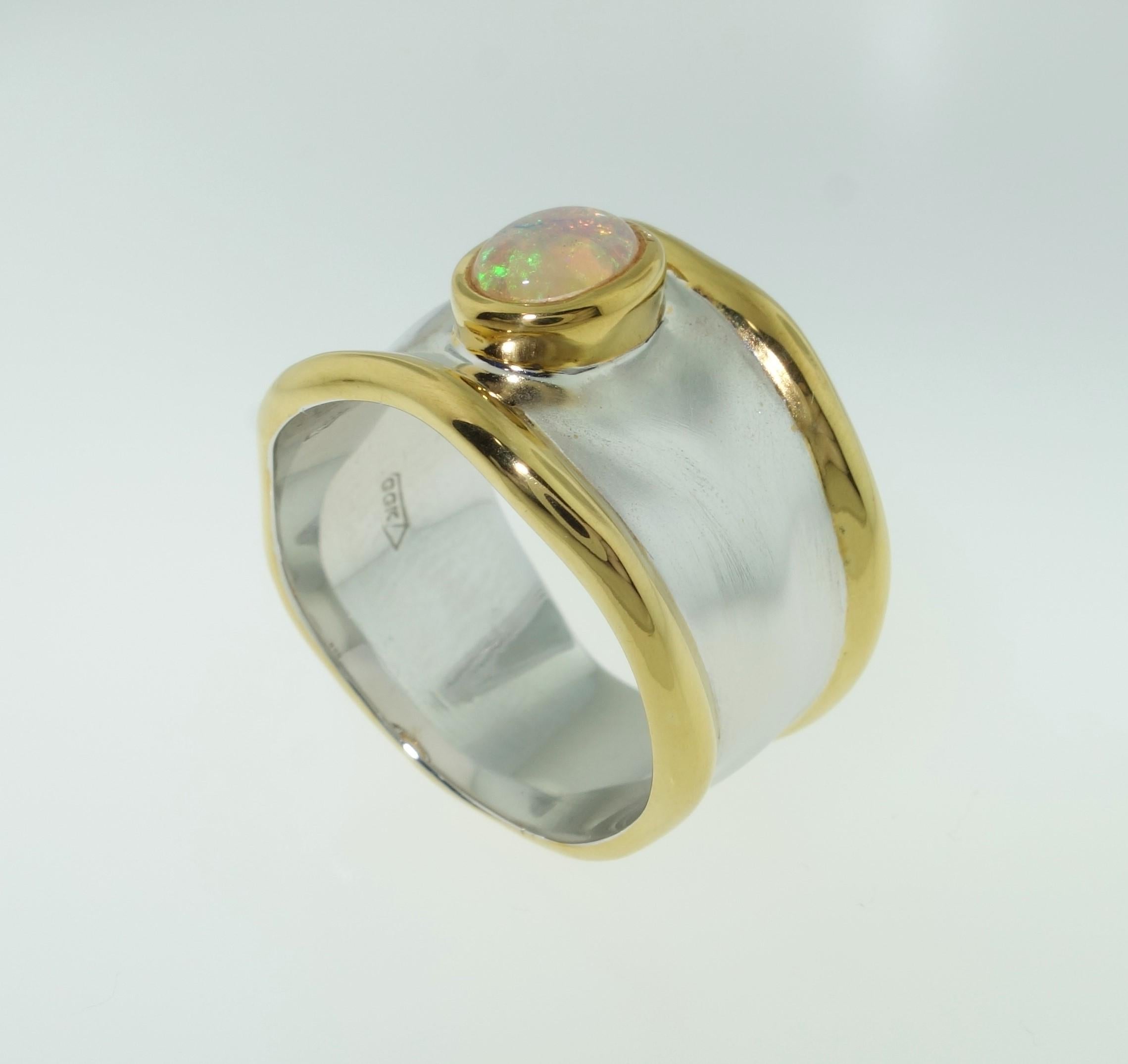 Beautiful solitaire ring featuring an Ethiopian Opal;  approx.  .42 carat; Sterling Silver Tarnish-resistant Rhodium and gold plated accents on either side of mounting; Size 8; we offer complimentary ring re-sizing. Classic and Classy…illuminating