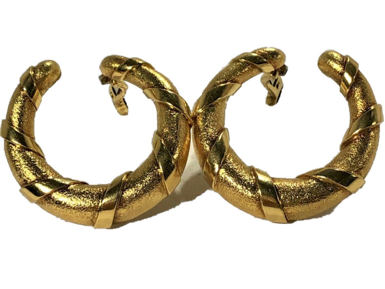 These lovely French Cartier  hoop earrings are crafted from 18k yellow gold and have a 1 3/16 inch outer diameter. The finely stippled finish is wrapped with  a high polish belting that gives an organic feel to the pair. They are signed CARTIER