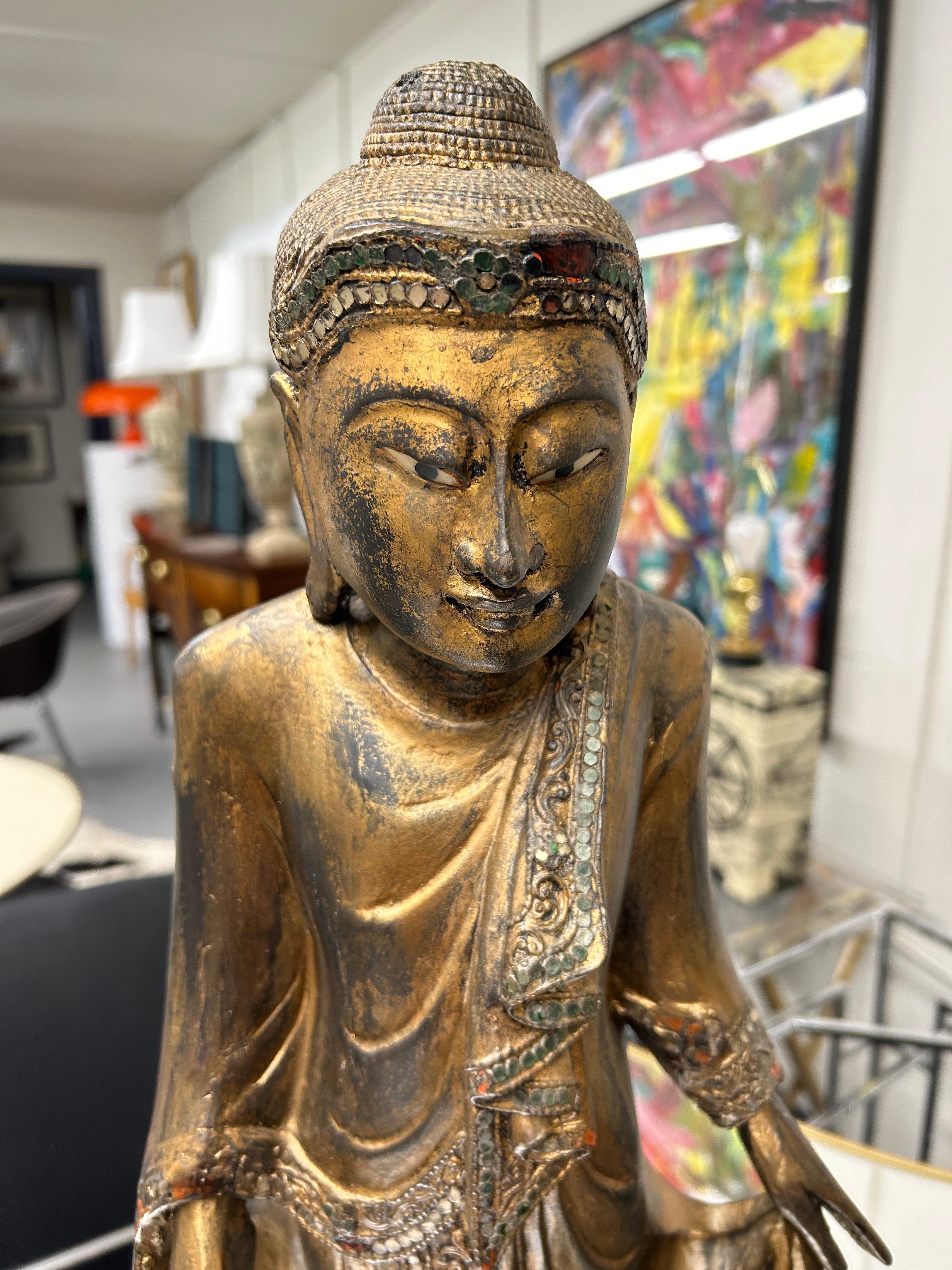Bouddha classique thaïlandais en bois doré à la pose sereine, monté sur un socle en bois ébonisé plus récent.