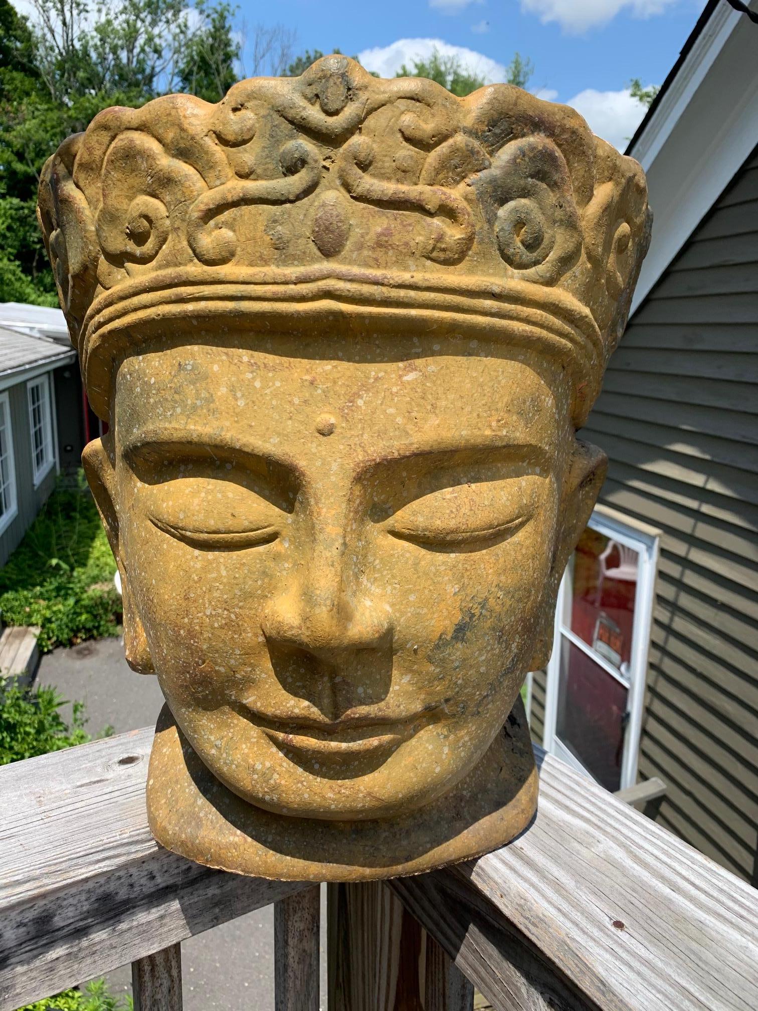 A large striking glazed terracotta Buddha head statue with crown and contented expression. A great addition to the patio, garden, or indoors.