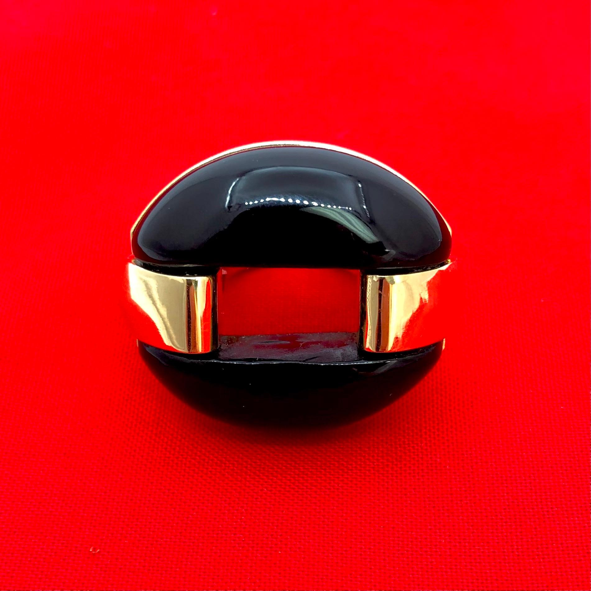 This striking and impactful ring is crafted from 18k yellow gold atop which sits a custom cut, black onyx oval measuring 1 3/16 inches by 1 1/16 inches. The stylish ring shoulders embrace the onyx oval on each side creating a visually stunning