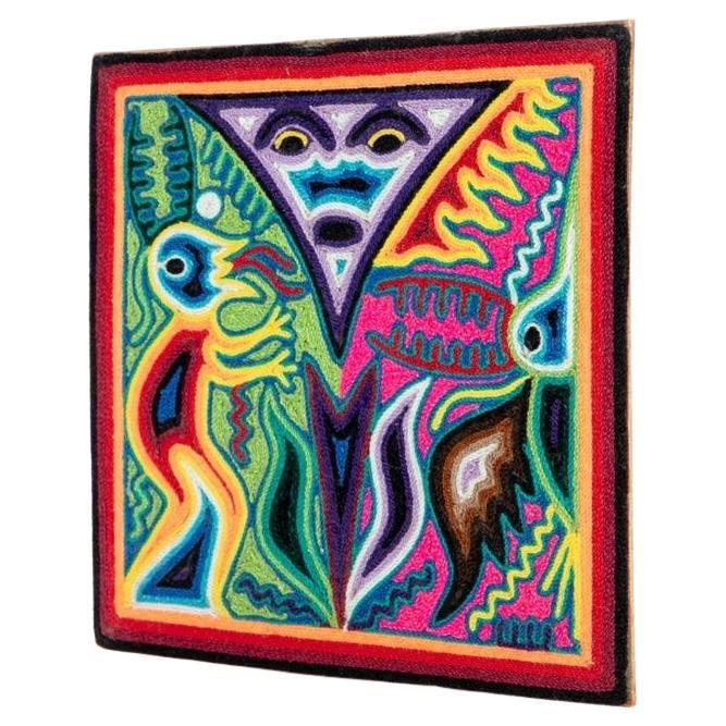 A small Huichol Yarn Painting on wood board with striking Color and vivid imagery by Artist Gabriel Bautista. The colors range from deep pinks, cobalt, red, yellow, orange and green to deeper blacks, and browns. The imagery is of a central floating