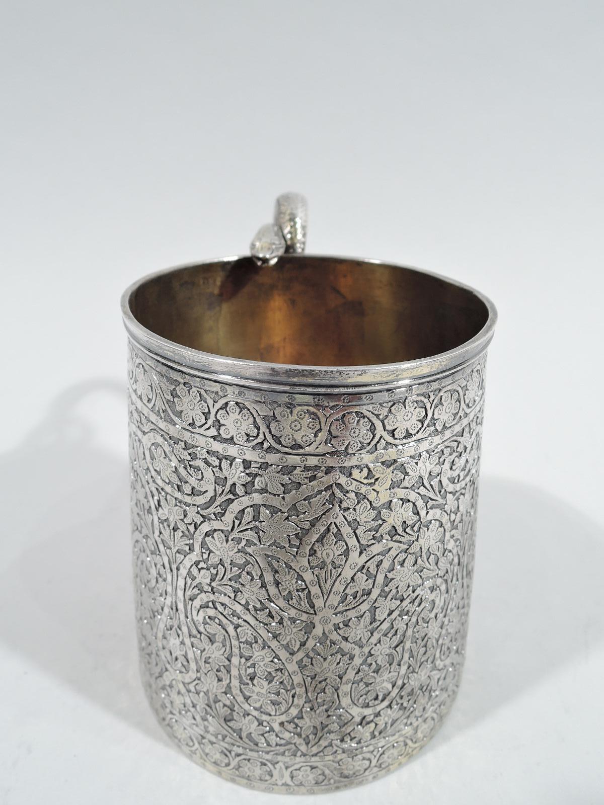 Striking Indian Colonial silver mug, 19th century. Straight and upward tapering sides worked with dense scrolls and flowers. Scrolled and scaly snake handle with head resting on rim. Gilt interior. Unmarked. Weight: 7.5 troy ounces.