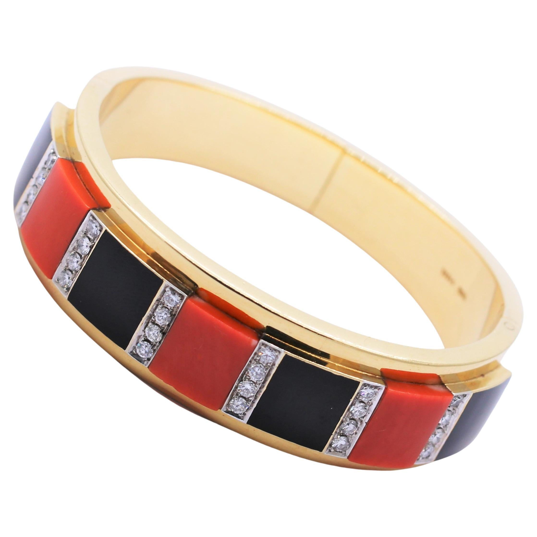 This tailored, mid-20th century bangle bracelet is sleek and very wearable. The rich 18k yellow gold exhibits the patina that takes many decades 
to develop. The contrast between the bright white diamonds, orange Mediterranean coral and jet black