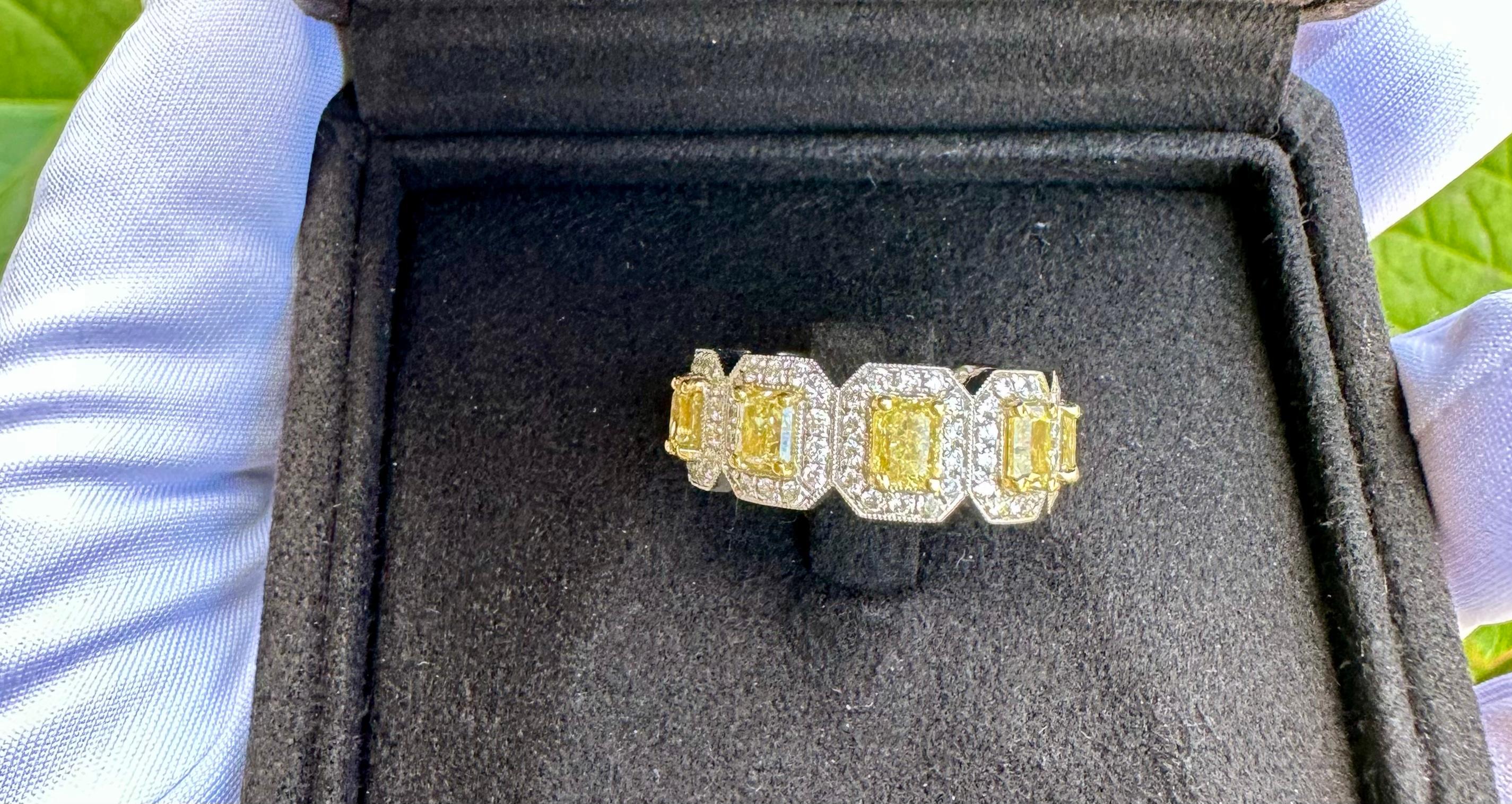 Very striking, ladies 18 karat white and yellow gold custom made 5.26 carat estate eternity band adorned with 9 radiant cut fancy yellow solitaire diamonds, prong set and surrounded by a halo of round brilliant white diamonds to further showcase