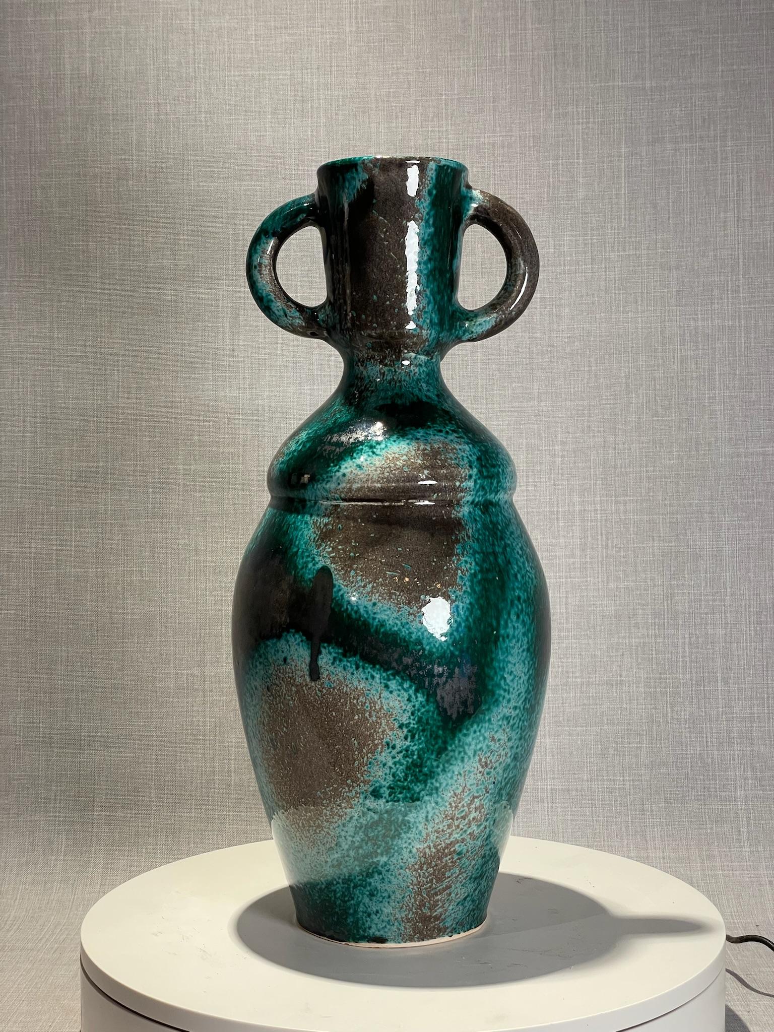 Ce vase frappant en céramique moderne du milieu du siècle présente une forme audacieuse et artistique, parfaite pour les collectionneurs et les amateurs de design. Ce vase à la silhouette inspirée des amphores est rehaussé par deux grandes poignées