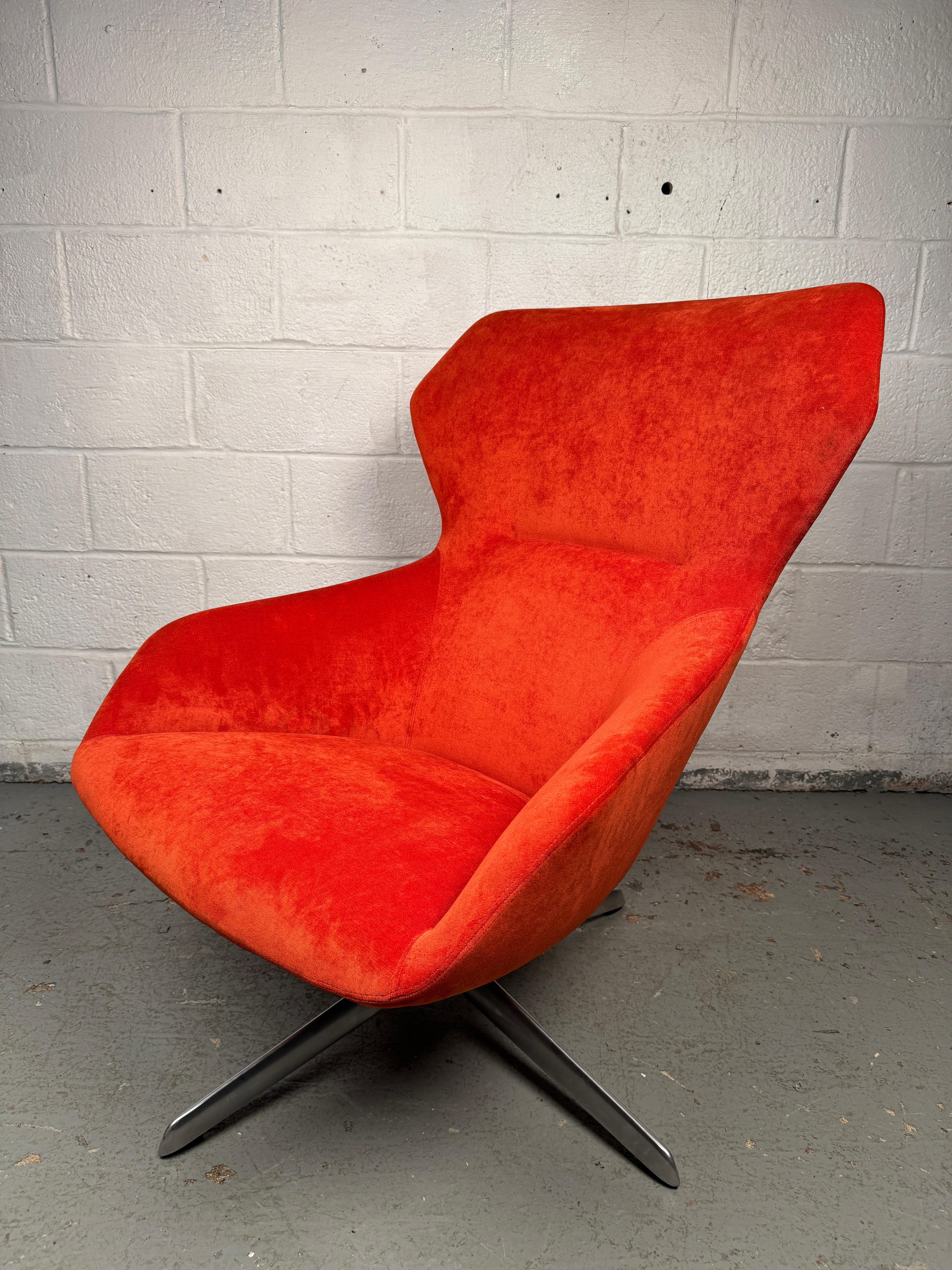 Eye-catching mid-century lounge chair upholstered in vibrant red fabric, designed with clean modern lines and a comfortable, low profile. The bold color and sculptural form make it both a functional seat and a statement piece, perfect for adding