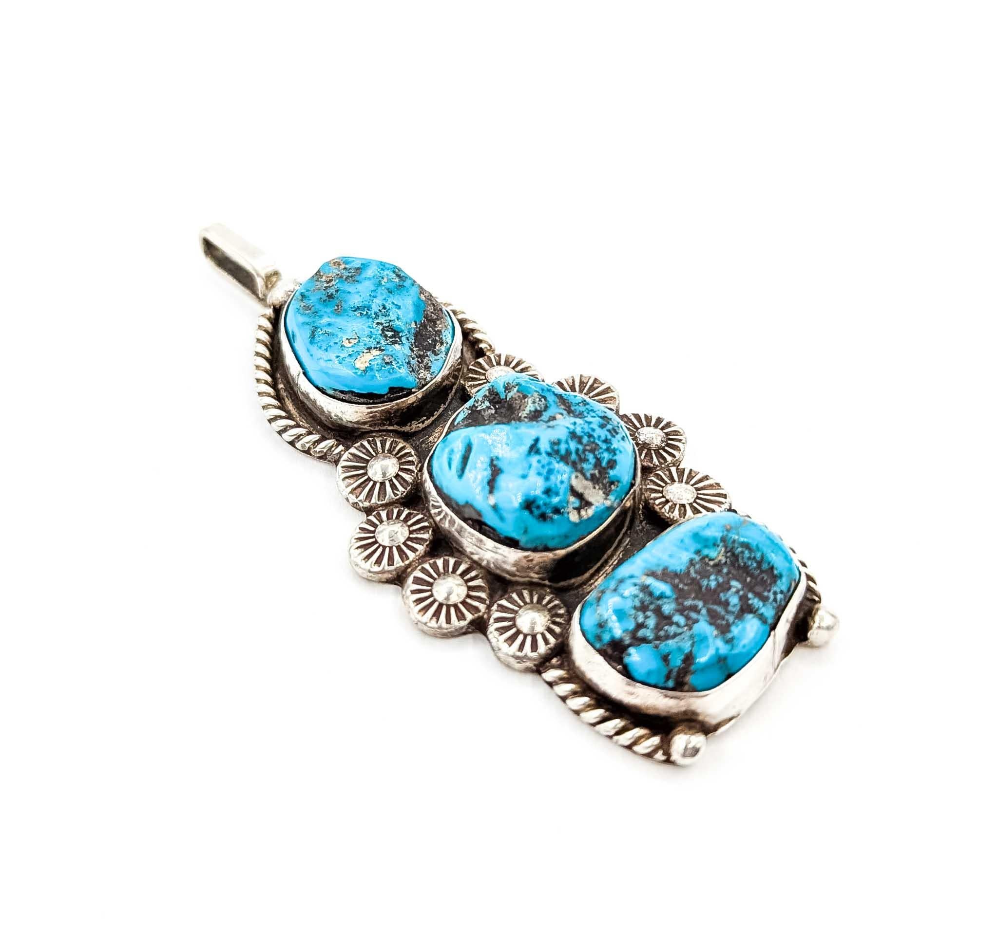 Questo audace ciondolo dei Nativi Americani mostra tre vibranti cabochon di turchese con motivi a matrice naturale, ciascuno incastonato in argento sterling. Con un'impressionante dimensione di 71,4 mm per 31 mm e un peso di 25,4 grammi, ha una