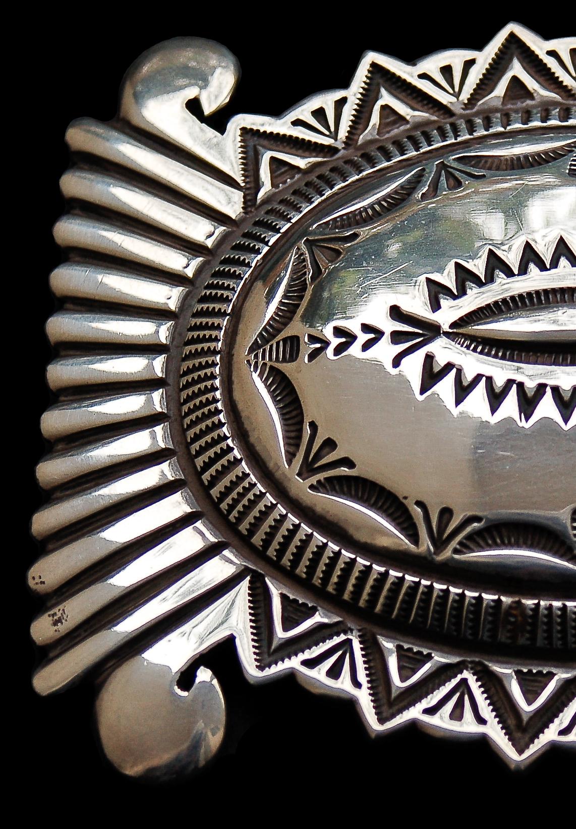 This outstanding belt buckle of heavy sterling silver exhibits all the beautifully detailed stamp work that has become a hallmark of master Navajo Silversmith Wilson Jim's work. 

Signed, 