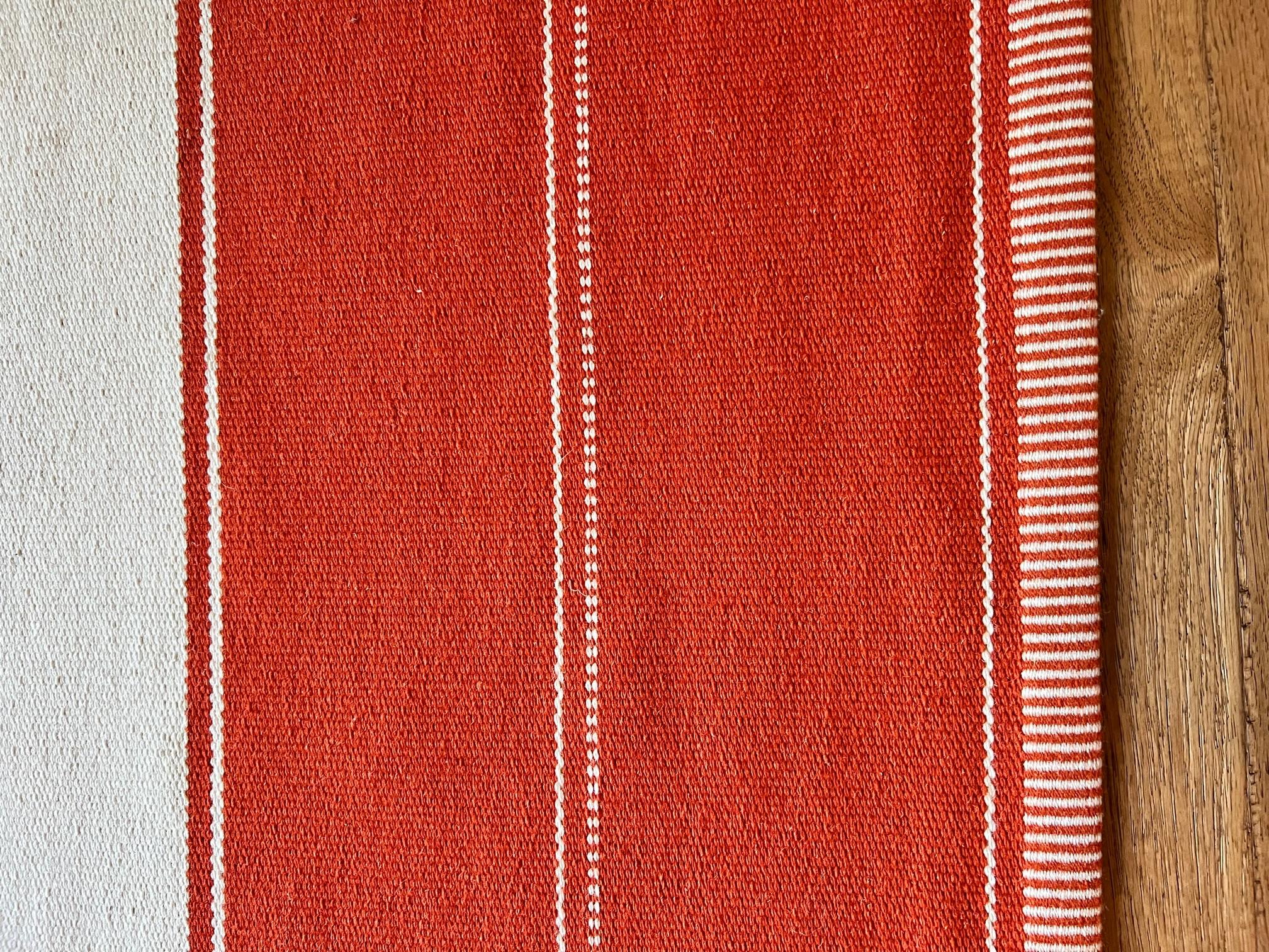 Dark orange and white striped wool rug by renowned Swedish rug manufacturer Kasthall. The design is by lead designer Gunilla Lagerhem Ullberg. This classic wool rug is made according to old Swedish weaving traditions. Available for customization in