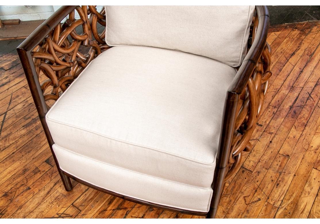 Fascinating and Sculptural design of interlaced rattan sides and back in a dark stain. With white linen like upholstered separate back cushion with a zipper. The lower seat cushion in one piece with the frame. Fine craftsmanship and quite