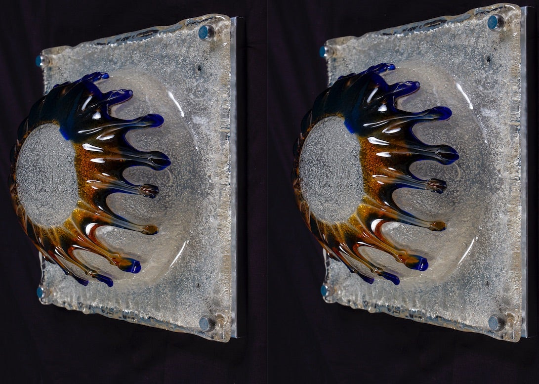 A pair of massive and original Italian wall lights or ceiling lights designed by Toni Zuccheri and produced by Venini Murano, model Patchwork, chrome metal frame 1970s. 
Striking handmade sconces with a blue and amber patchwork become a work of
