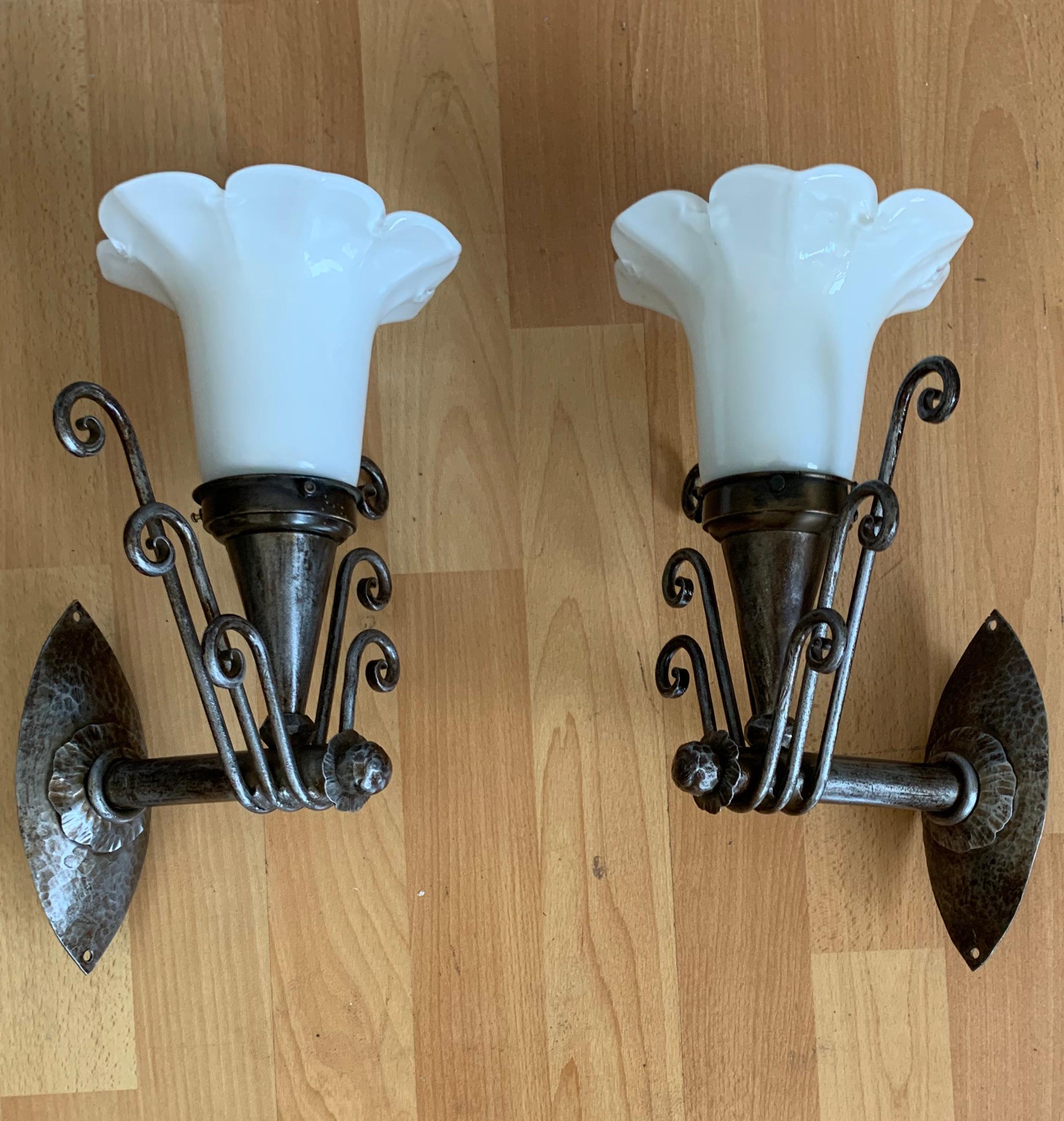 Wonderfully stylish and all handcrafted wall lights from the Arts & Crafts era.

If you are looking for a unique pair of quality crafted and highly decorative wall sconces then these hand forged iron and mouth blown glass sconces could be perfect.