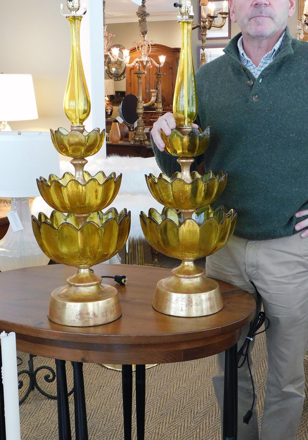 Each tall lamp composed of a baluster stem above three graduated lotus leaf cups interspersed with giltwood dividers; all raised on a giltwood base.