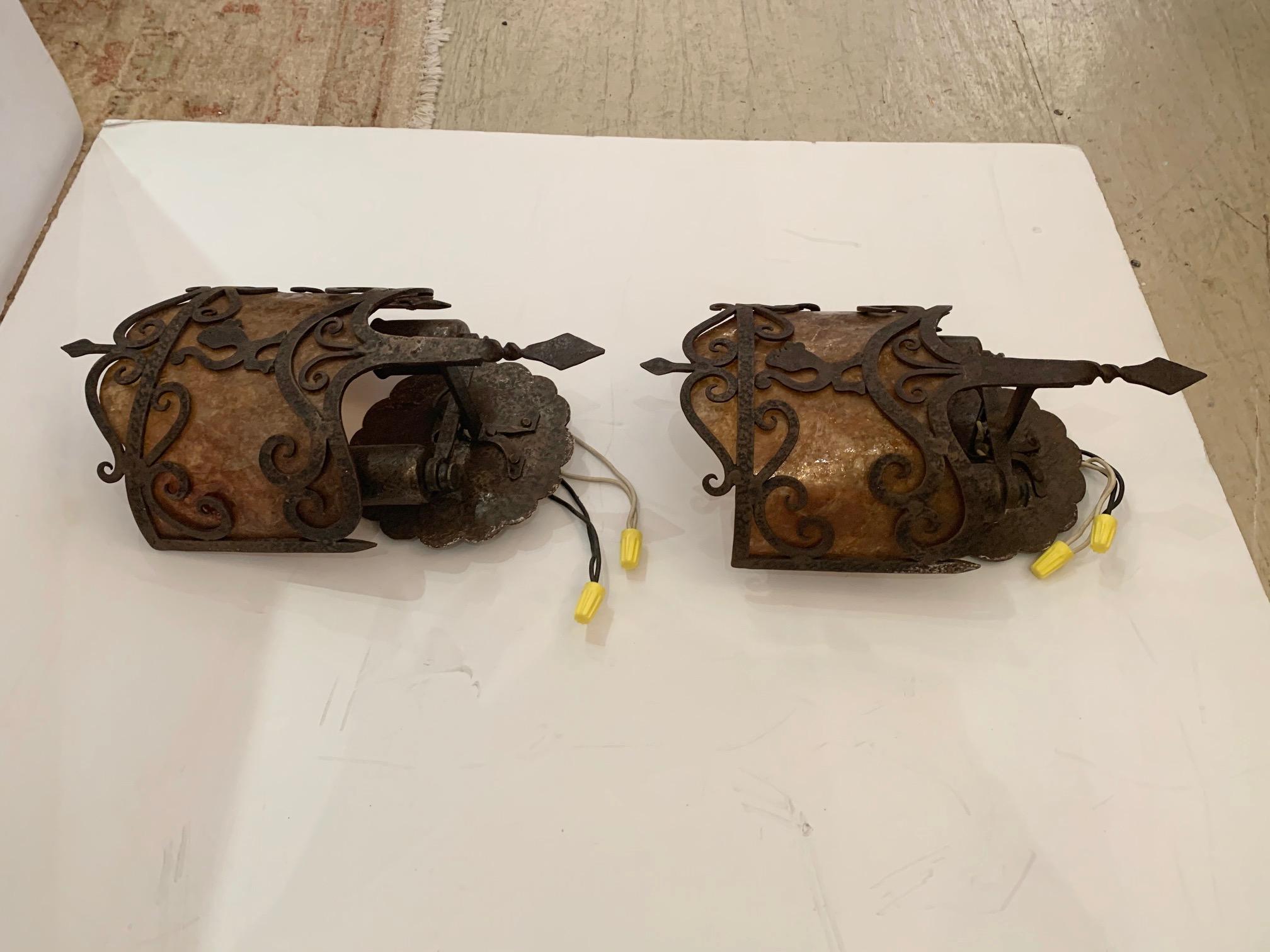 Handsome pair of antique gothic sconces made of stunning hand forged iron and having original mica shades.


 