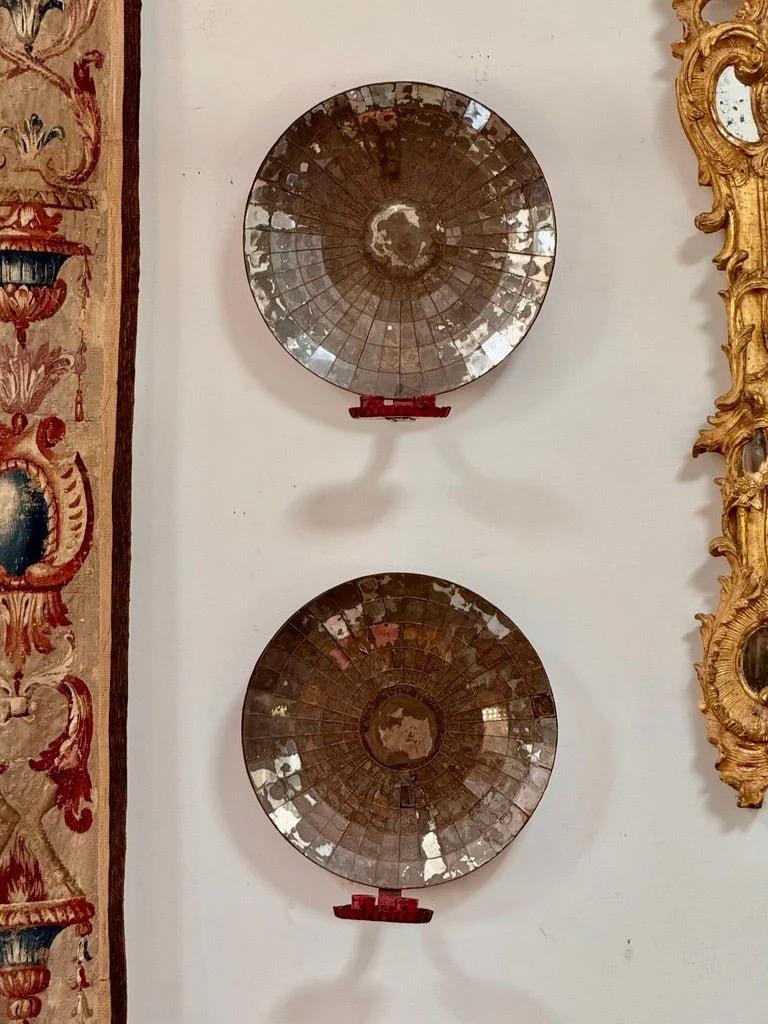 A striking pair of late 19th-century wall sconces. featuring mirrors composed of individually cut and set rectangular mirror segments. The glass retains its original silvering, now beautifully patinated with age and oxidation. Each piece is mounted