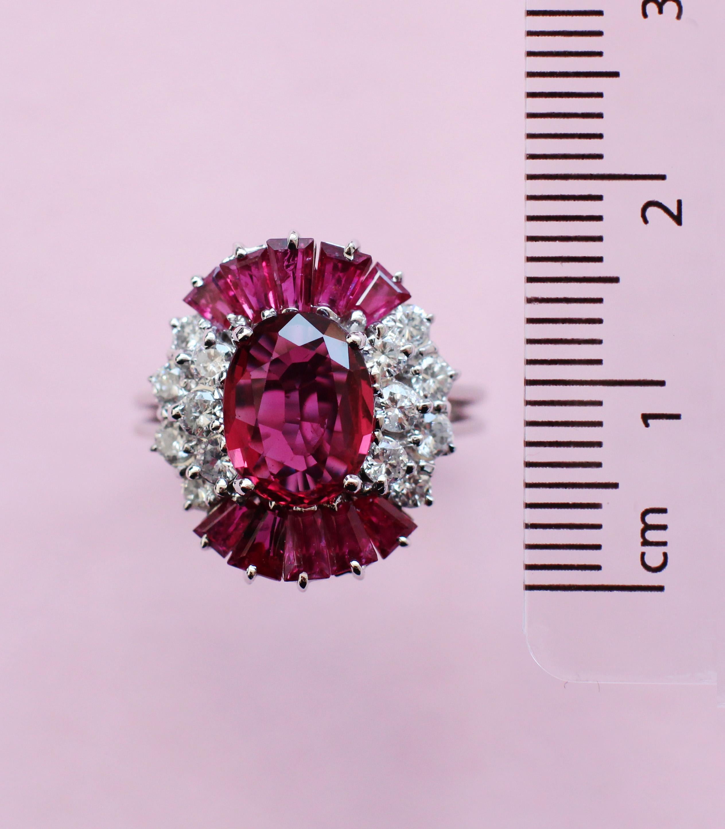 This vintage-style ring makes a big impression thanks to its unique design by the Haruni family. It boasts a sensational oval ruby in a vivid purplish red colour at its centre, with smaller baguette rubies featuring amongst the mostly white diamond