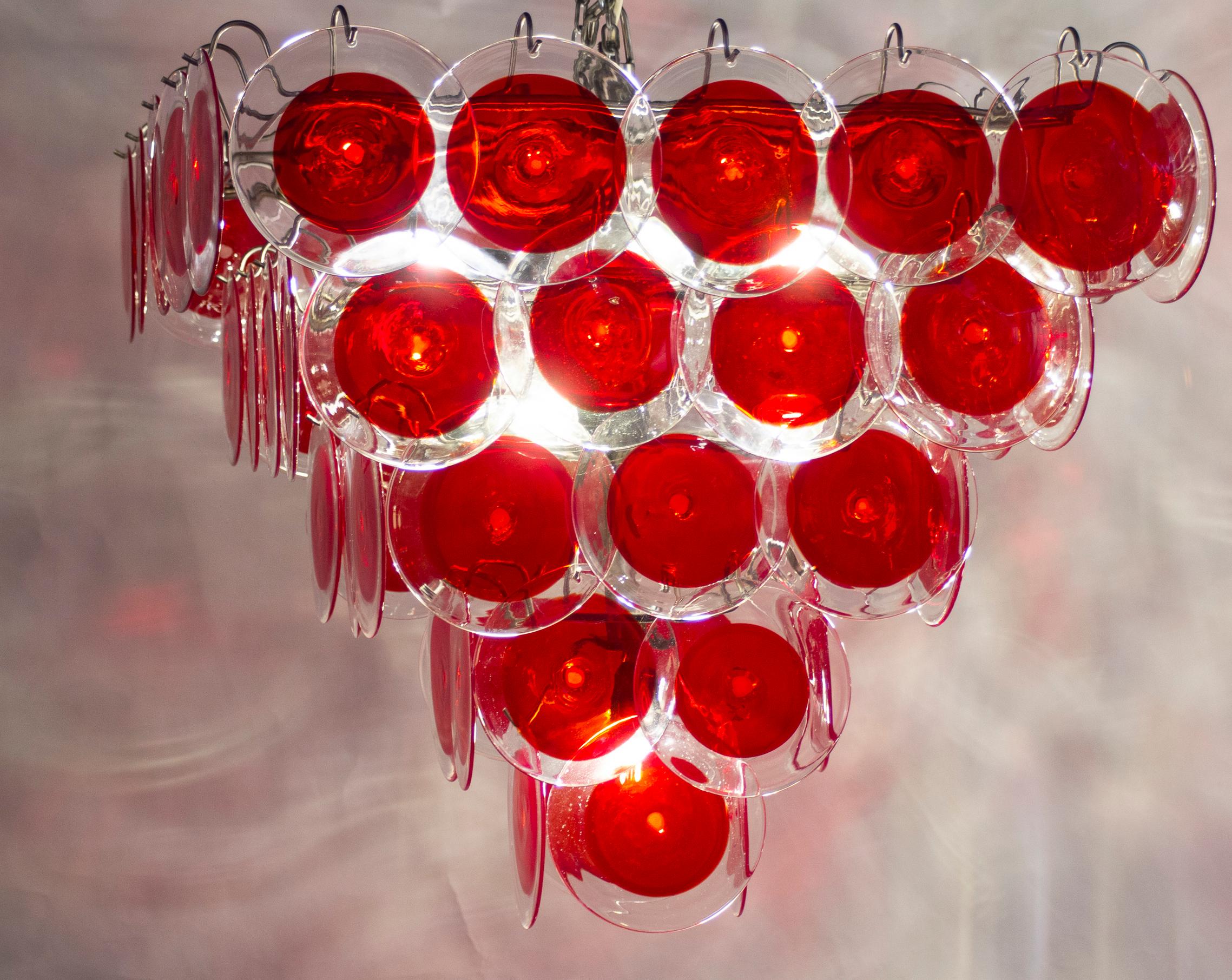Red Murano glass disc chandelier in pyramid shape. 
Each chandelier is made of 60 red discs of precious Murano glass and arranged on five levels.
Customization is available in different sizes, finishes and glass colors.
 Nine light bulbs E 27.