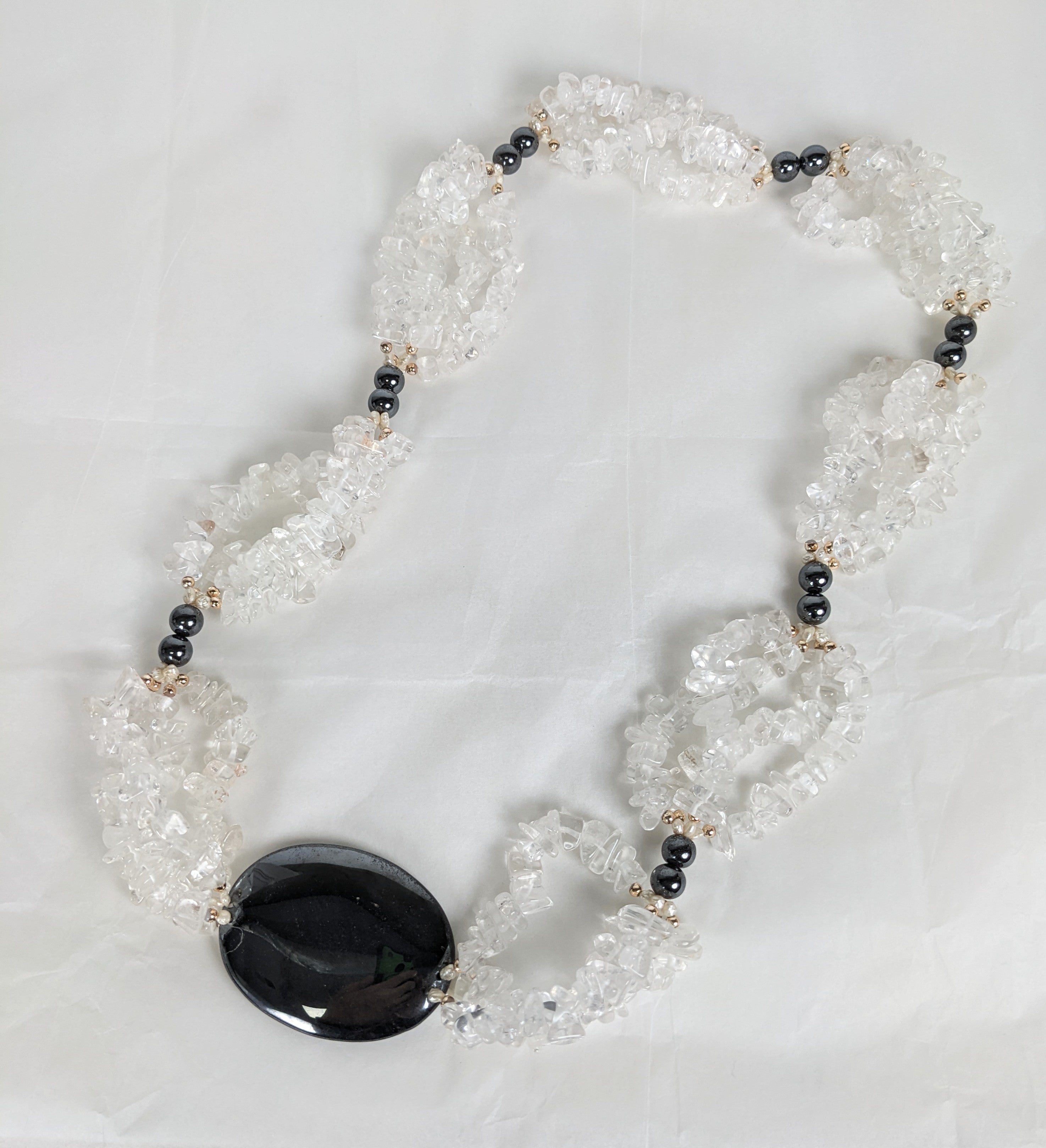 Un sorprendente Sautoir in cristallo di rocca ed ematite degli anni '80. Le stazioni di cristallo di rocca burattato sono intervallate da perle di ematite, perle d'acqua dolce e perle dorate con un grande pendente ovale in ematite. Si infila sopra