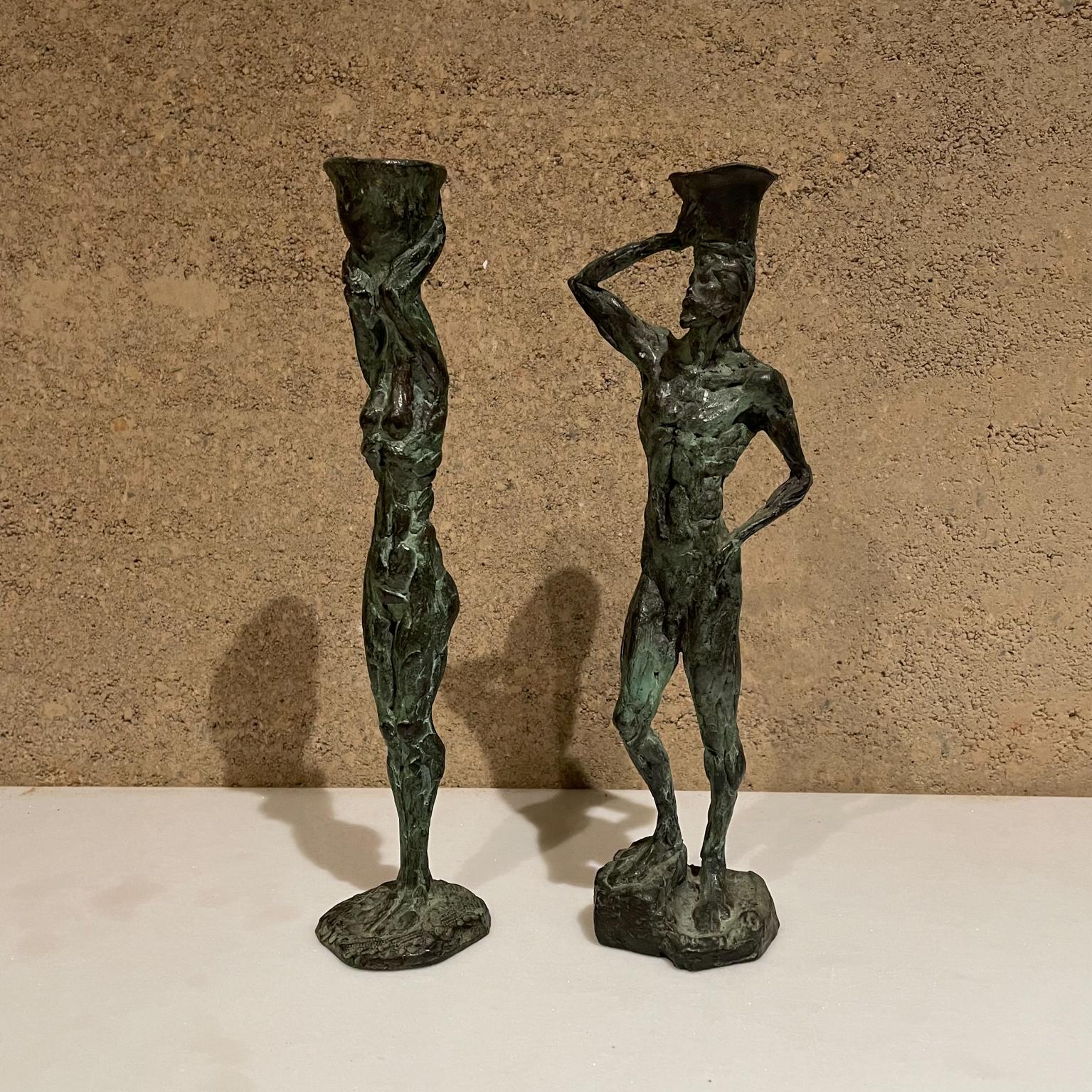 Bronze sculpture candleholders
Midcentury striking pair of bronze sculptures function as candleholders. 
Signed with artist name, A. Moreno. Mexico 1960s
In the style of Diego Giacometti. 
Dimensions: 11 tall man, 4.5 W x 2.5 D women, 2.5