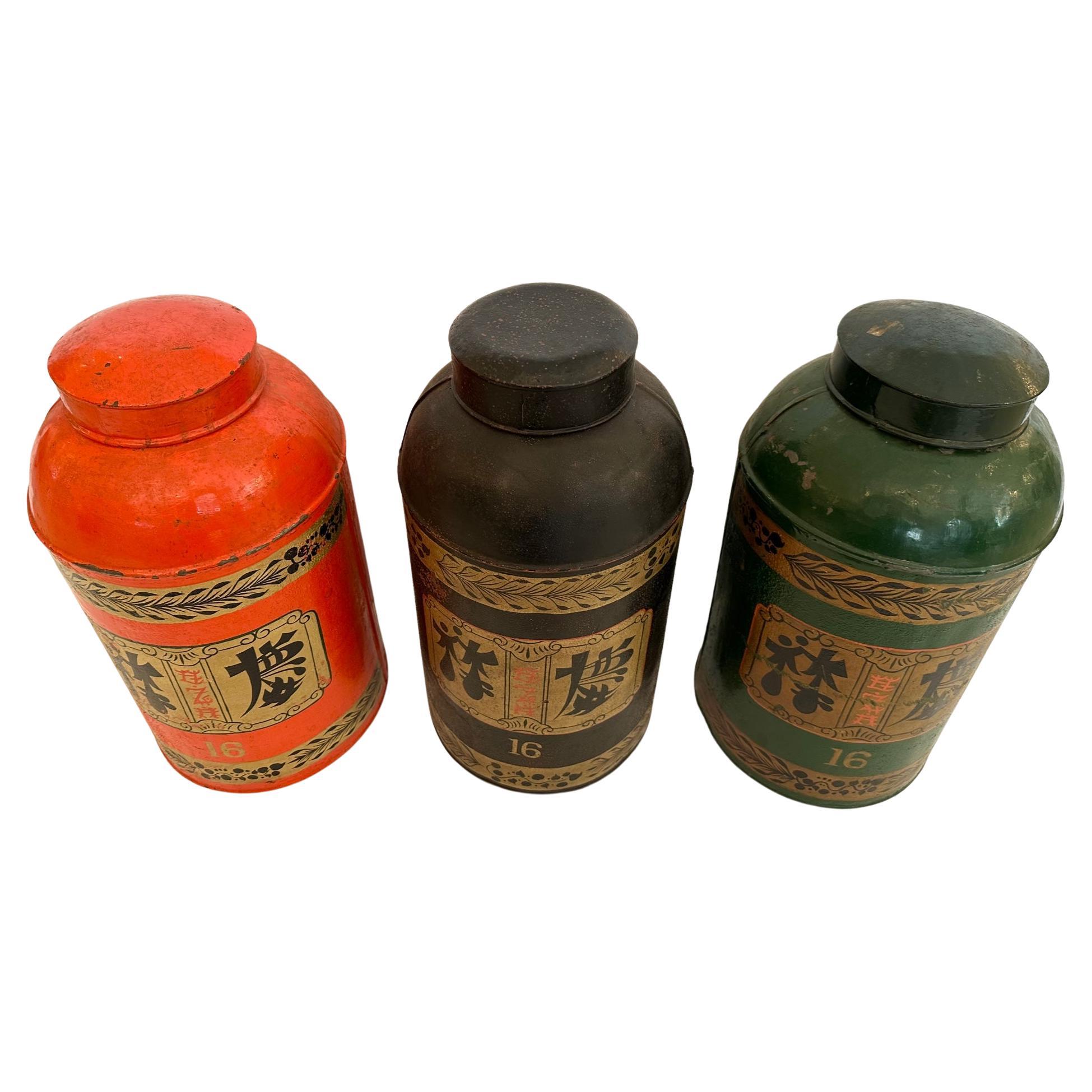 Striking large set of 3 antique metal hand painted Chinese tea canisters having wonderful graphic decoration.  Colors are orange, black and green.