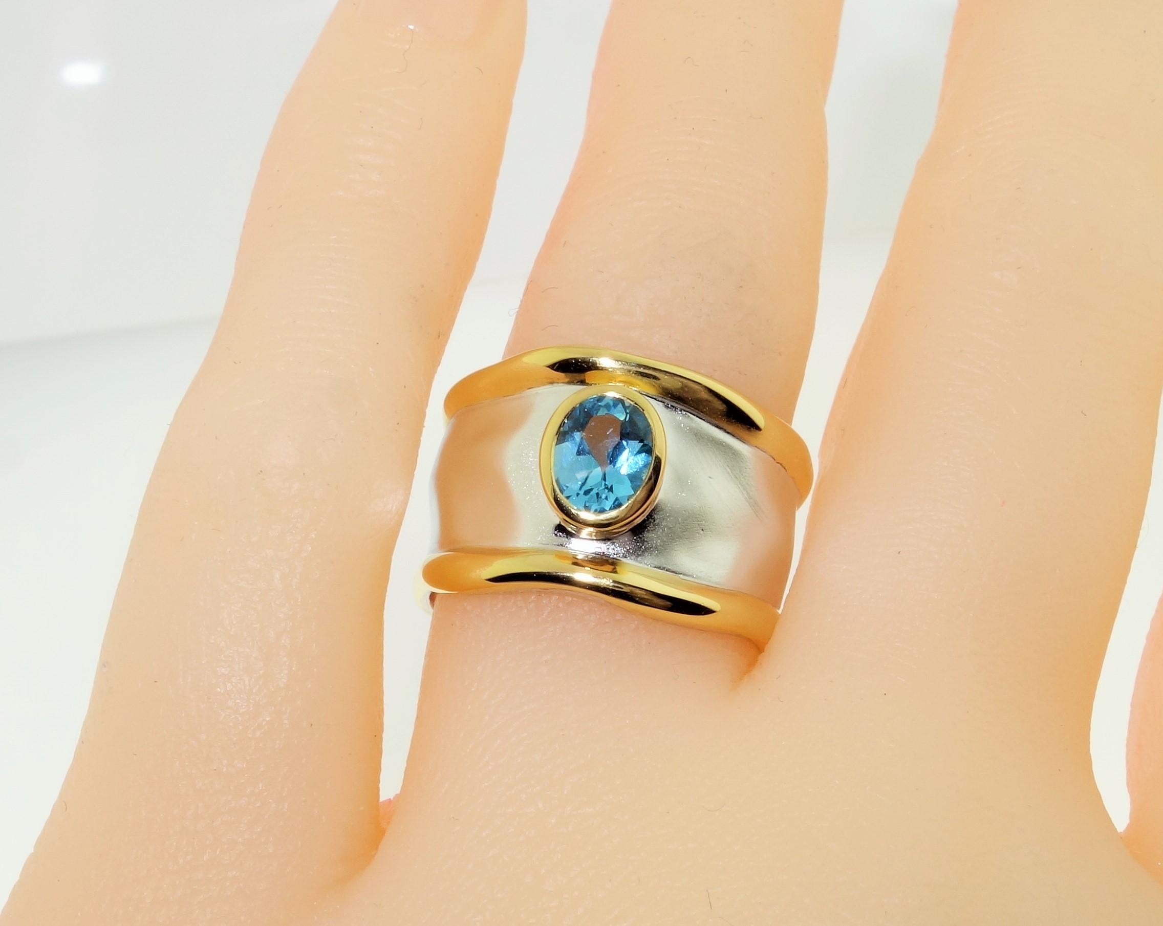 Beautiful solitaire ring featuring an oval Swiss Blue Topaz; approx. 0.71 carat; approx. stone size: 6mm x 5mm. Sterling Silver Tarnish-resistant Rhodium and gold accents on either side of mounting. Size 7. Classic and Chic…illuminating your look