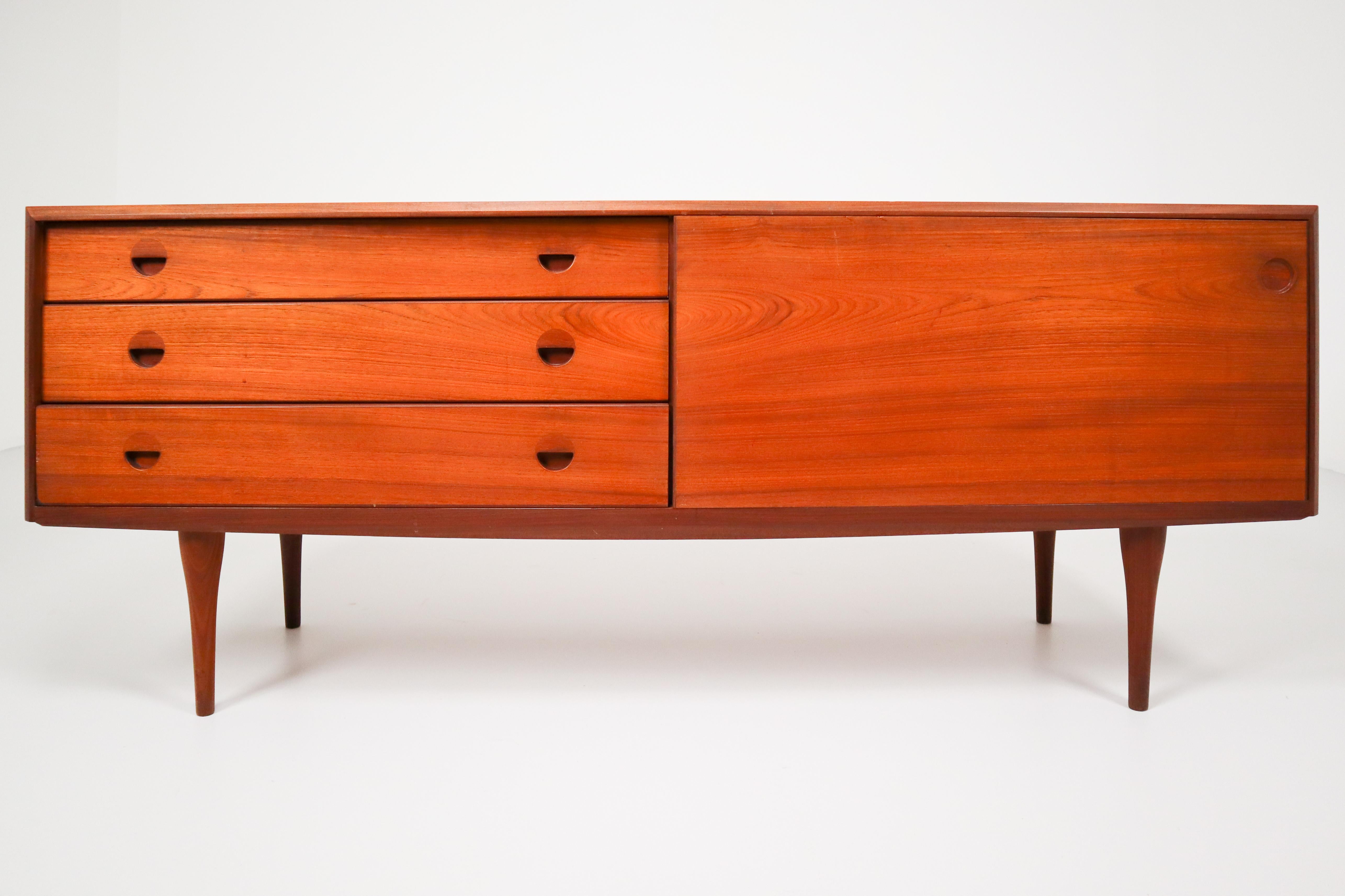 Striking teak sideboard from the 1960s made in Denmark in a smooth design where the beautiful wood grain falls into focus on the sliding doors and three drawers. This sideboard will contribute to a luxurious character of the interior. Preserved in