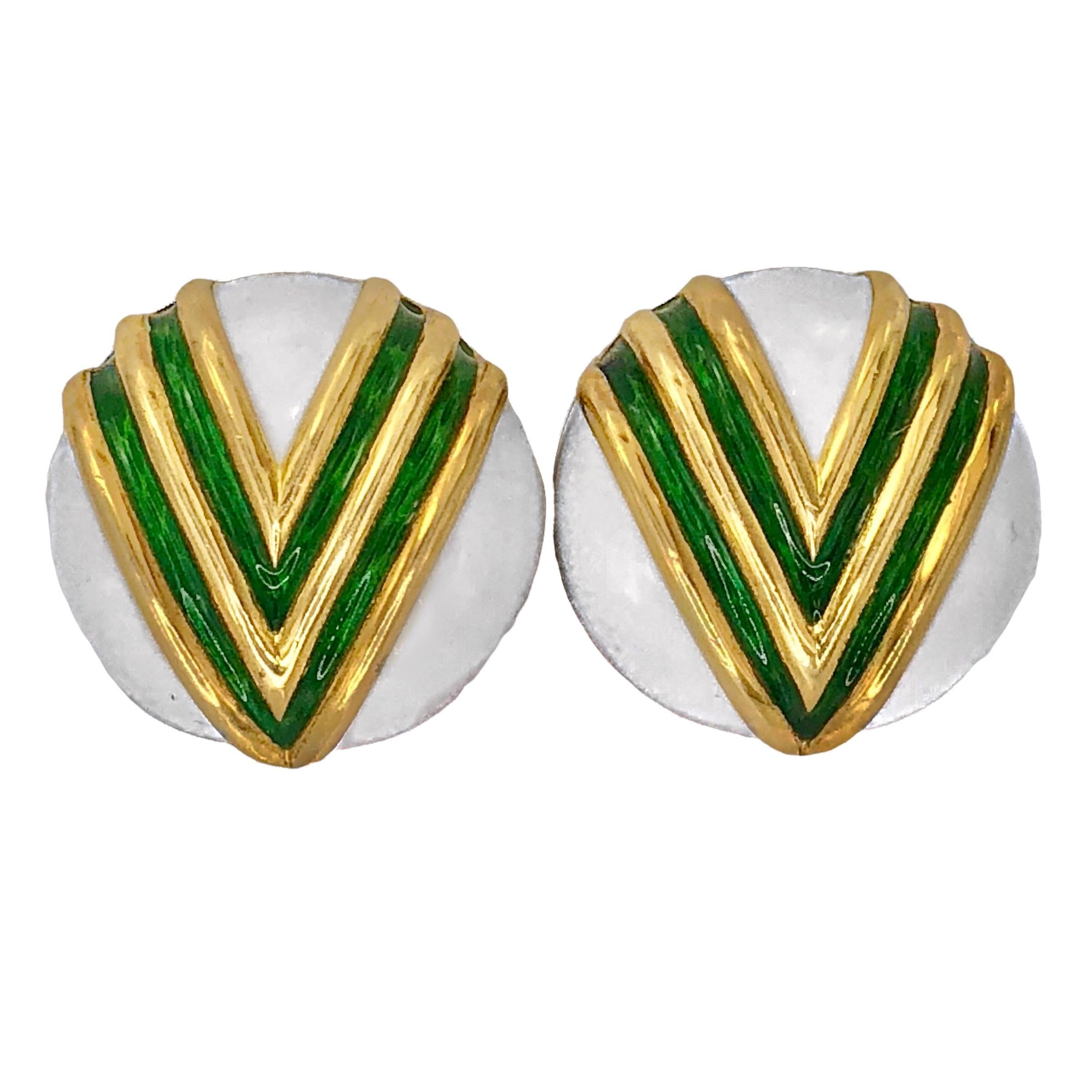 This unique pair of Tiffany & Company 18K yellow gold round, white enamel earrings are accented with a striking double chevron design in green enamel. Measures 7/8 inches in diameter. Equipped with fold down omega style clip backs.  Signed Tiffany &