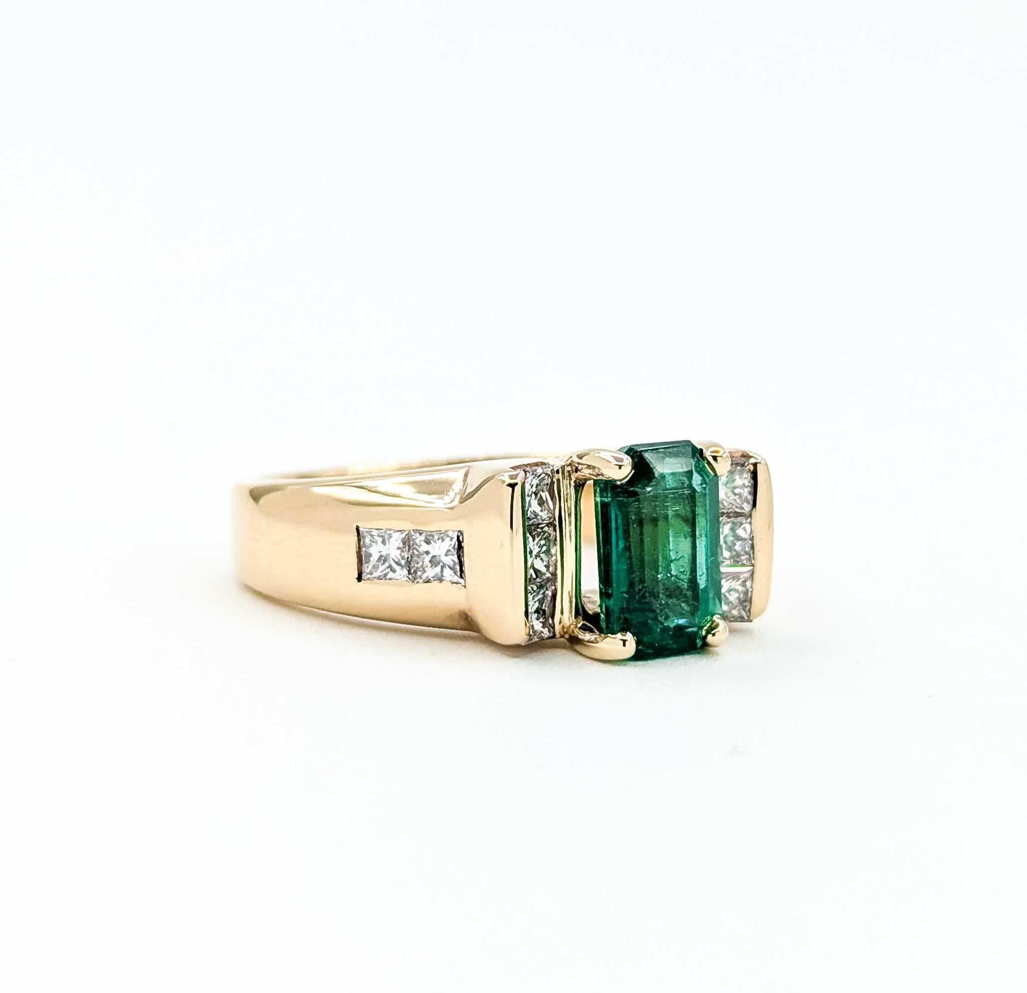 Dieser auffällige Vintage-Ring ist aus 14 Karat Gelbgold gefertigt und zeigt in der Mitte einen farbenprächtigen Smaragd im Smaragdschliff, flankiert von funkelnden Diamanten von insgesamt 0,50 Karat. Die nahezu farblosen Diamanten mit SI-Klarheit