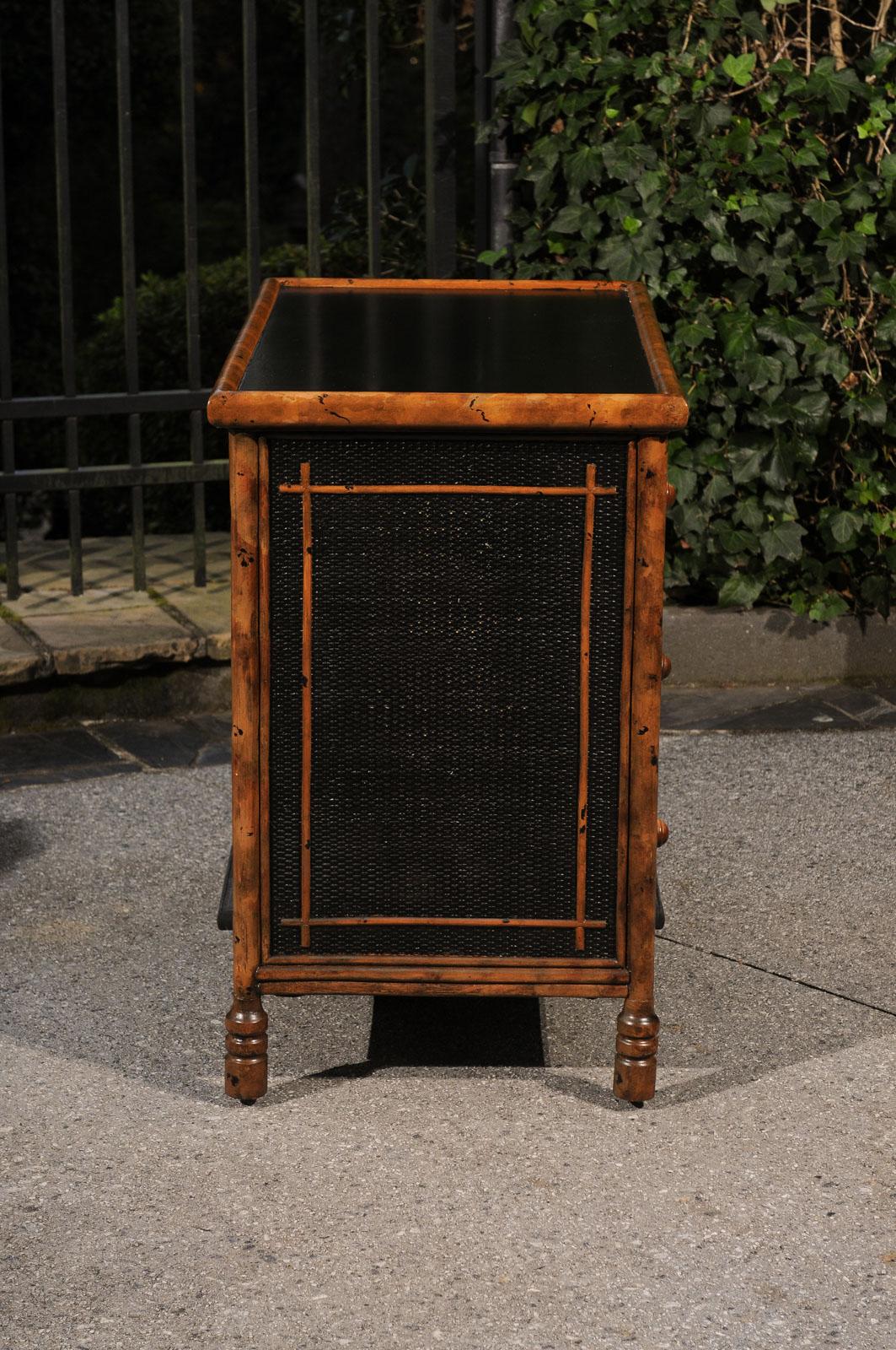 Un'imponente cassapanca vintage in stile British Colonial, del 1980 circa. Robusta struttura in legno duro impiallacciato in canna con dettagli in rattan e bambù. La finitura in ebano è splendidamente ossidata per rivelare sottili accenti di canna