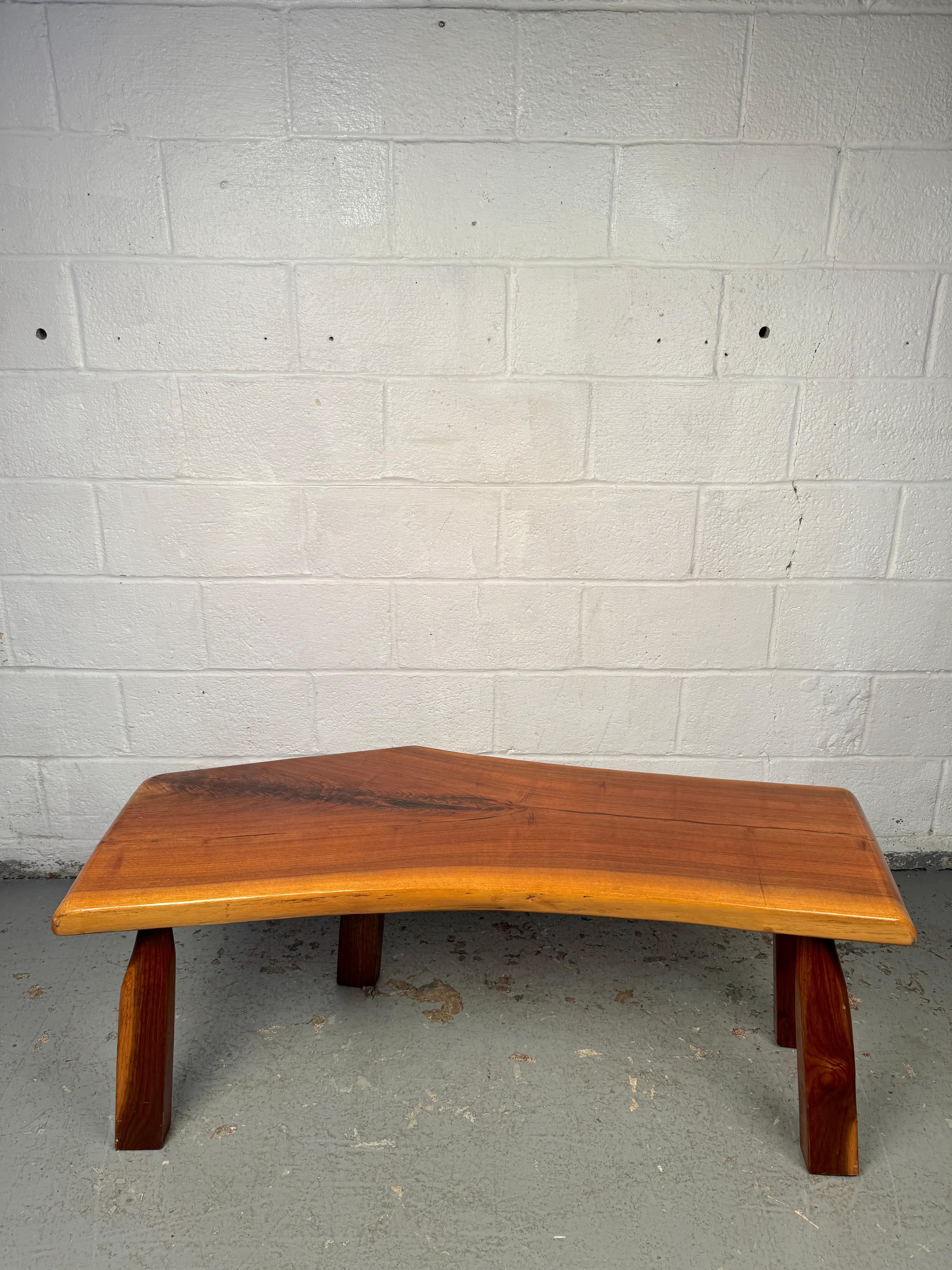 Table basse moderne du milieu du siècle, avec un plateau en bois naturel qui met en valeur la beauté organique du bois. La forme sculpturale associe un grain chaud à des lignes épurées, créant un équilibre parfait entre la nature et le design