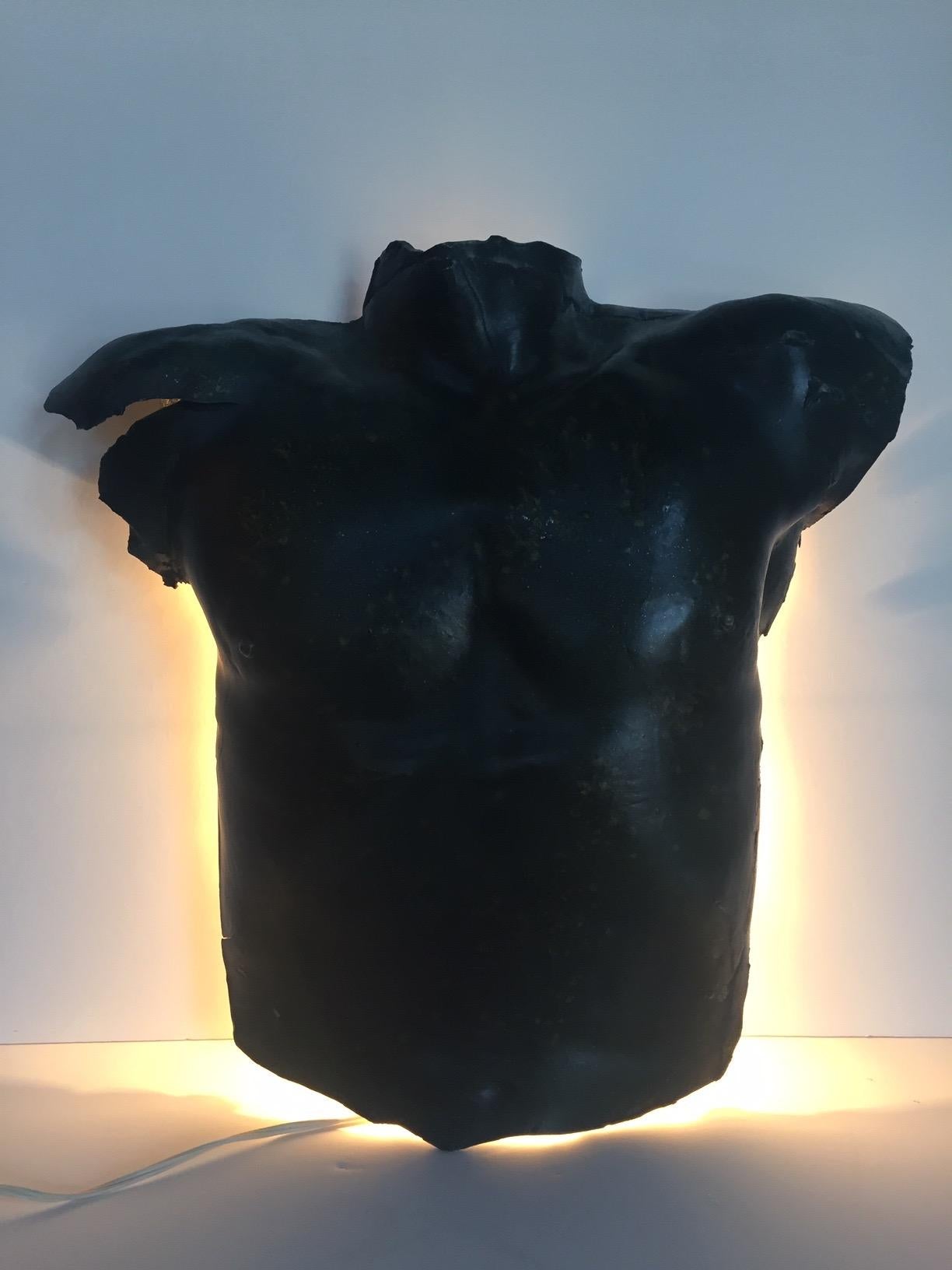 A handmade one of a kind wall sculpture sconce in the shape of a male torso that is electrified from behind. Plaster in a dark green made to look antique.