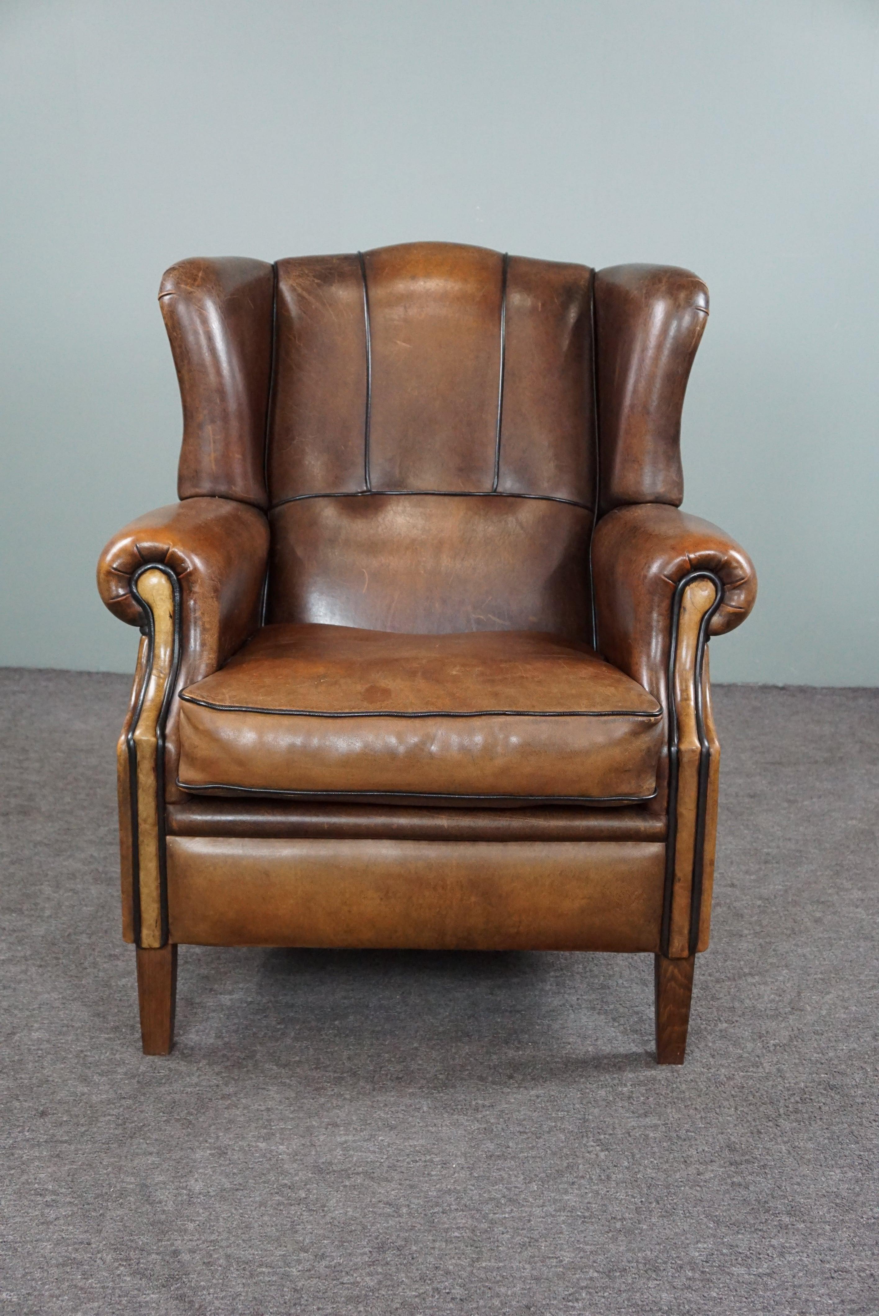 Offered is this well-fitting sheepskin leather wing chair with a very expressive division in the leather.

This strikingly colored and comfortable wing chair is a very good addition to almost any interior in terms of appearance and patina. The