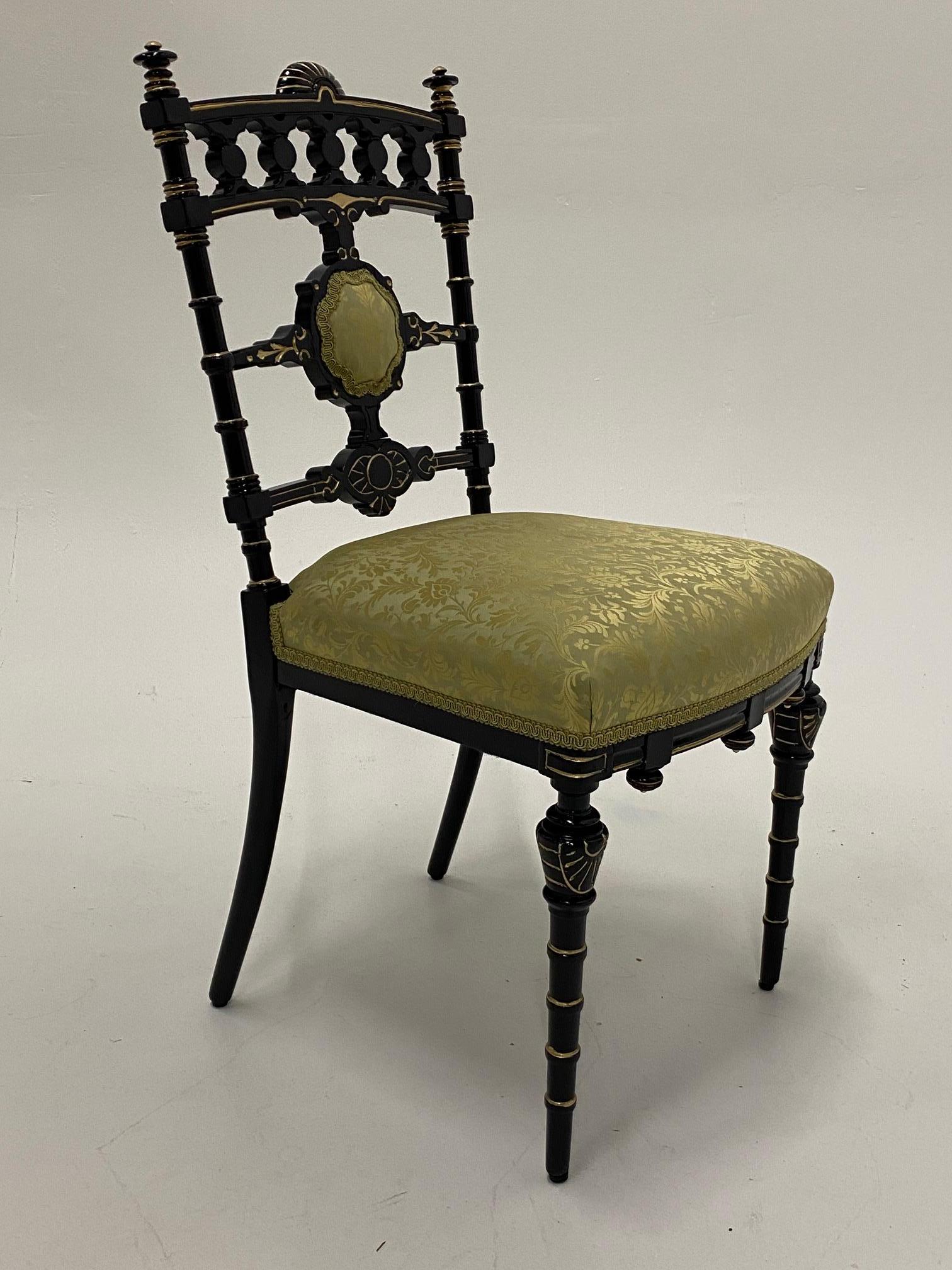 A strikingly decorative Victorian side chair having detailed carved ebonized wood and gilded frame offset with fancy chartreuse damask new upholstery.