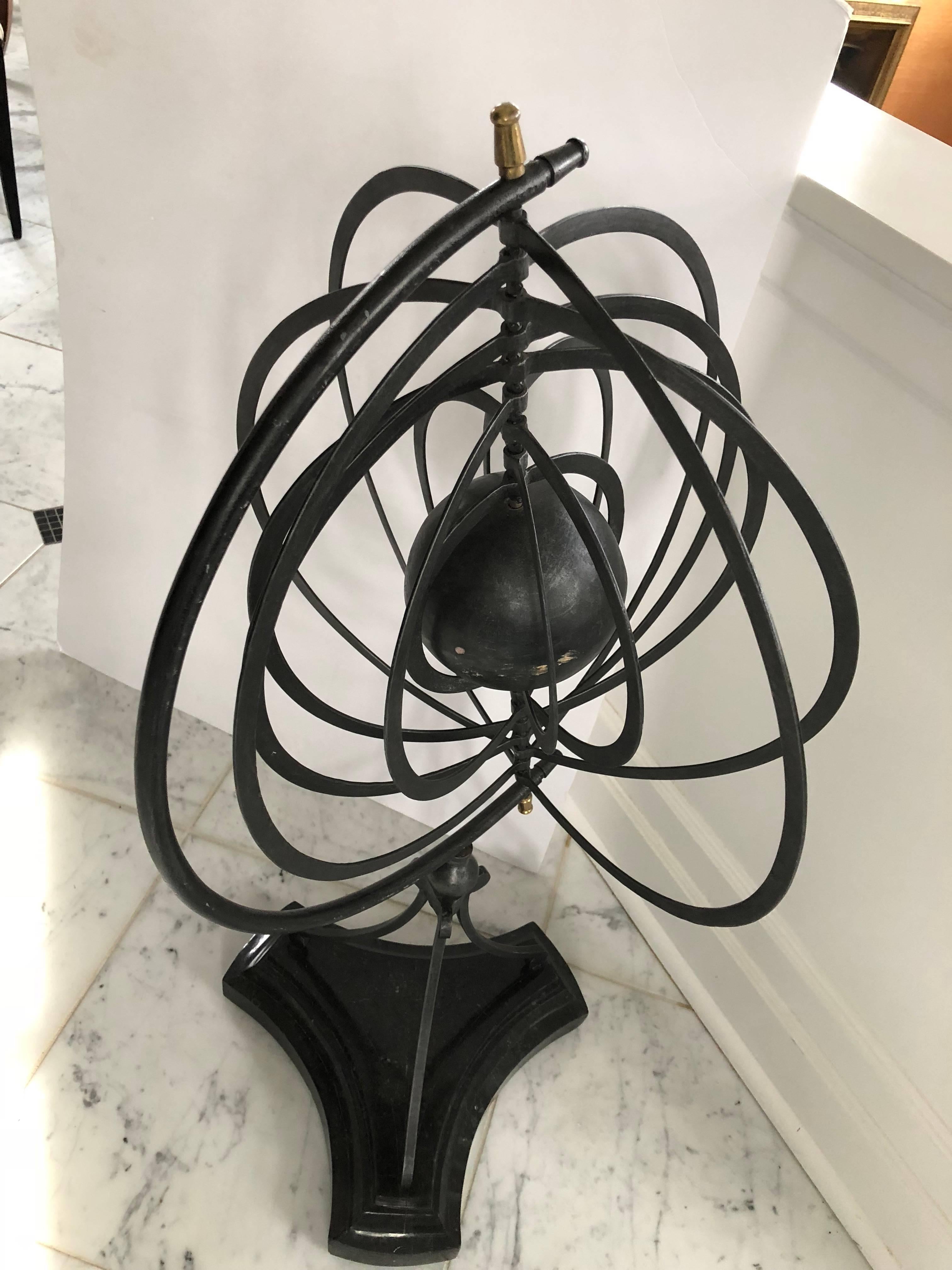 Strikingly large Maitland Smith armillary on a black tessellated base. Made of solid iron, the armillary measures 39” tall on a 12.5” base. There are nine iron rings that rotate around the inner sphere. The overall width of the rings is 23”. For
