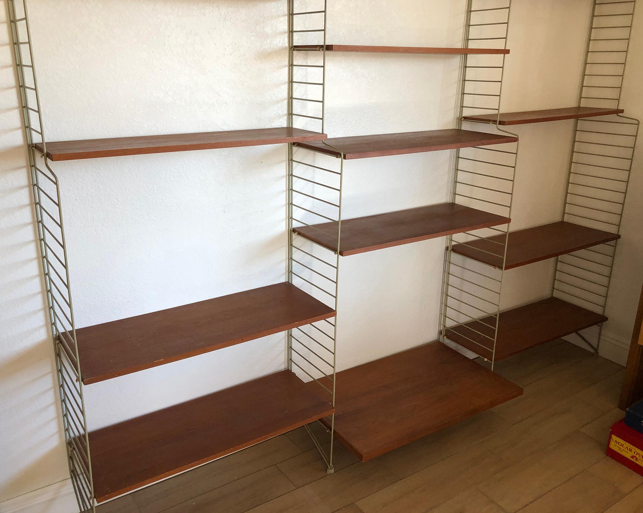 An absolutely gorgeous wall unit by Nils (Nisse) Strinning for String Design. This wall unit stands free against any wall and does not require any mounting hardware or screws. A great modern piece!

Metal brackets are off-white with hardwood teak