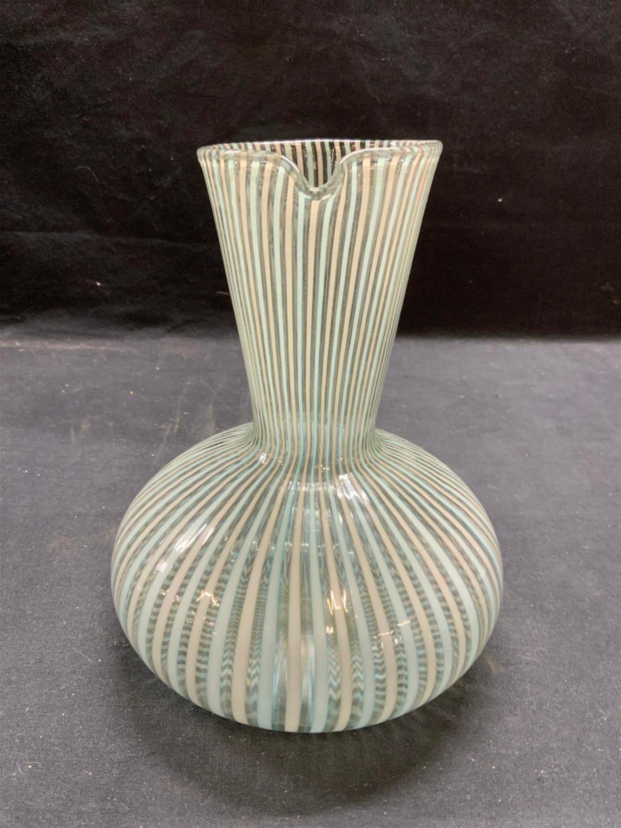 Small, striped glass carafe by Gio Ponti for Venini. 
This is an ‘A Canne’ or caned glass carafe or pitcher. It was produced in Italy at the Venini glass factory. In 1921 Venini and Cappellin opened a glass factory called Vetri Soffiati Muranesi